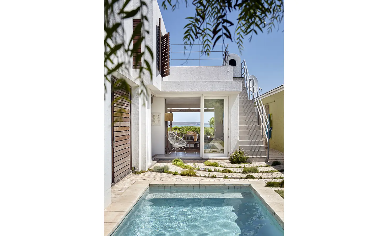 Perfect Hideaways: A serene courtyard with a sparkling plunge pool, surrounded by a white modern home with wooden shutters and an external staircase leading to the rooftop terrace. Blue Lagoon, Langebaan.