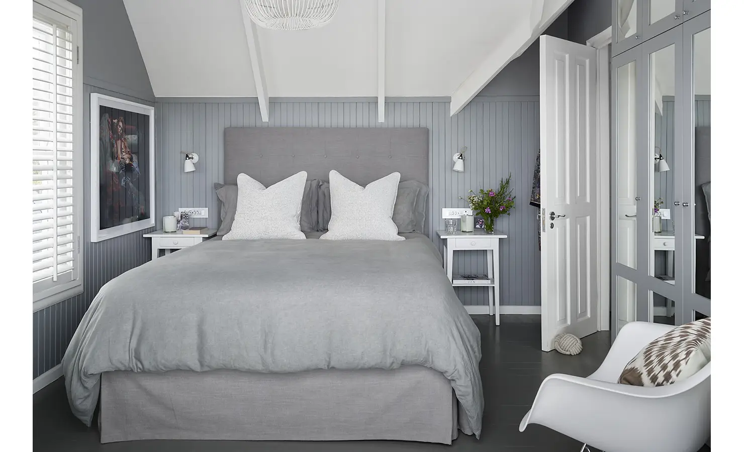 Perfect Hideaways: A serene master bedroom in soothing grey and white tones, featuring a double bed with plump pillows, vaulted ceiling with exposed beams, and mirrored wardrobes. Noordhoek Beach House, Noordhoek.
