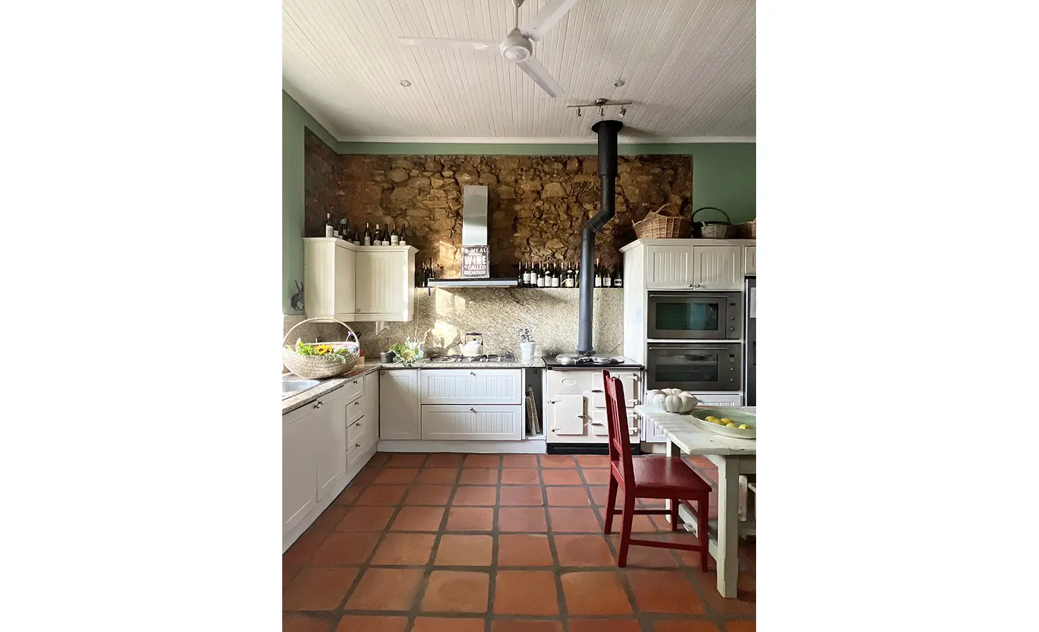 Perfect Hideaways: A rustic yet elegant farmhouse kitchen with terracotta floors, a stone wall, and a classic Aga stove, creating a warm and inviting atmosphere. Staart Farm, Paarl.