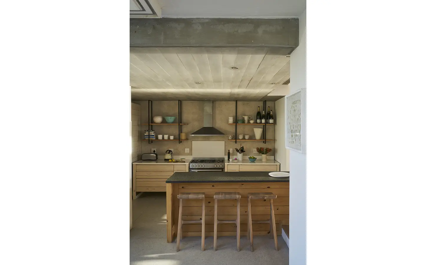 Perfect Hideaways: A modern rustic kitchen with an open-shelf design, a central wooden island with bar stools, and concrete accents that add an industrial yet warm touch. Blue Lagoon, Langebaan.