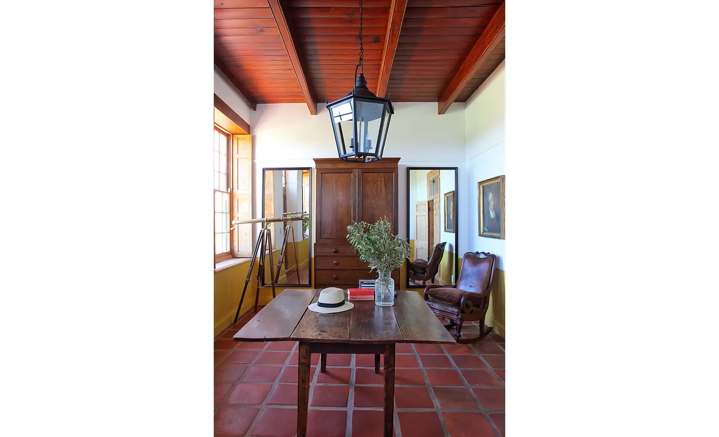 Perfect Hideaways: A sophisticated study with antique furniture, a telescope, and terracotta-tiled floors, illuminated by warm natural light. Penhill Manor House, Nuy Valley.