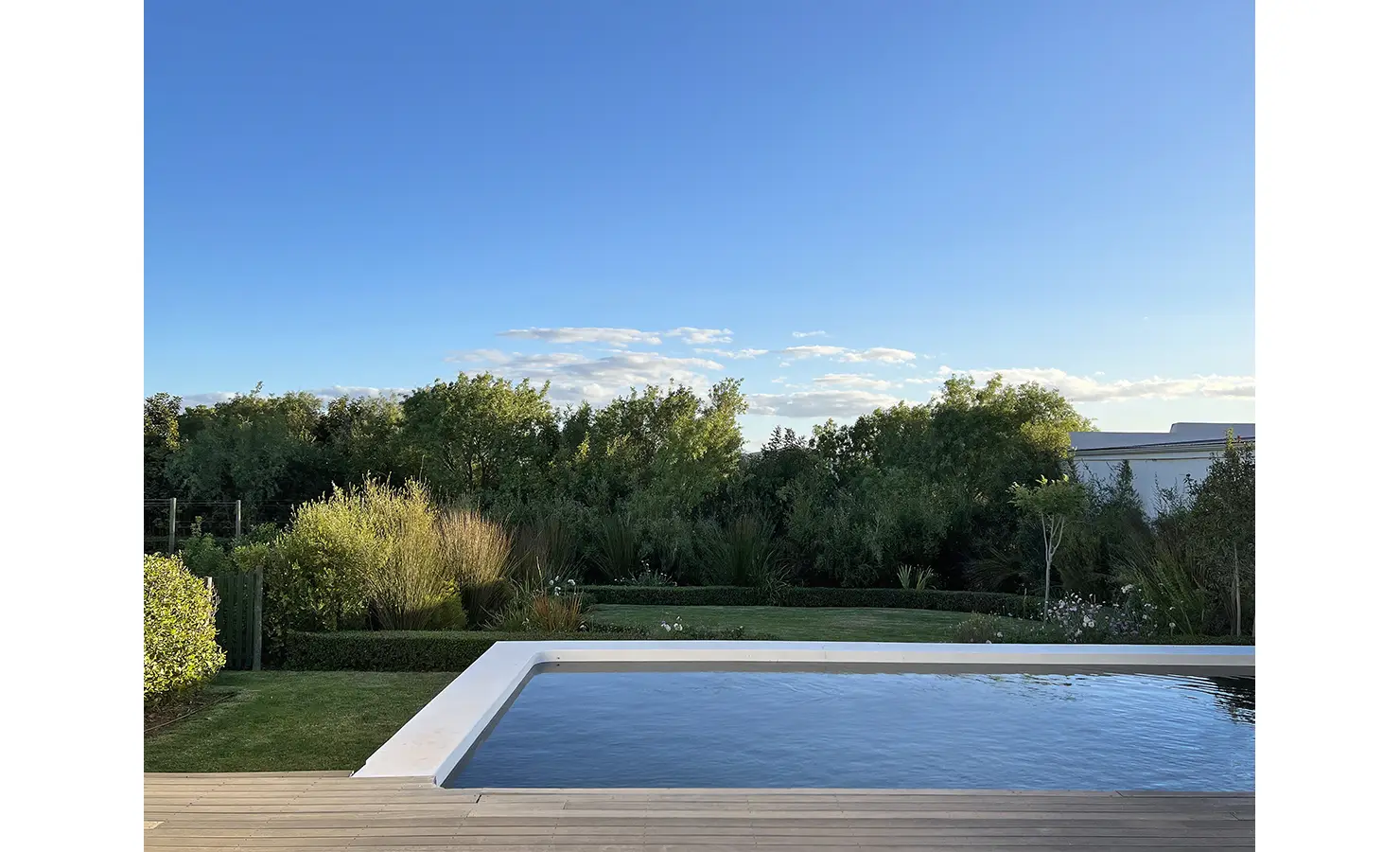 Perfect Hideaways: A serene poolside view with still water reflecting the vast blue sky, surrounded by lush greenery and a manicured garden. The perfect spot for relaxation in a tranquil countryside setting. Penhill Fruit Barn, Nuy Valley.