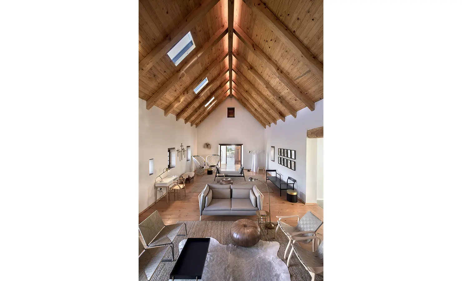 Perfect Hideaways: A vaulted living space with exposed wooden beams, minimalist furnishings, and warm neutral tones, creating a refined yet cosy atmosphere. Babylonstoren, Franschhoek.