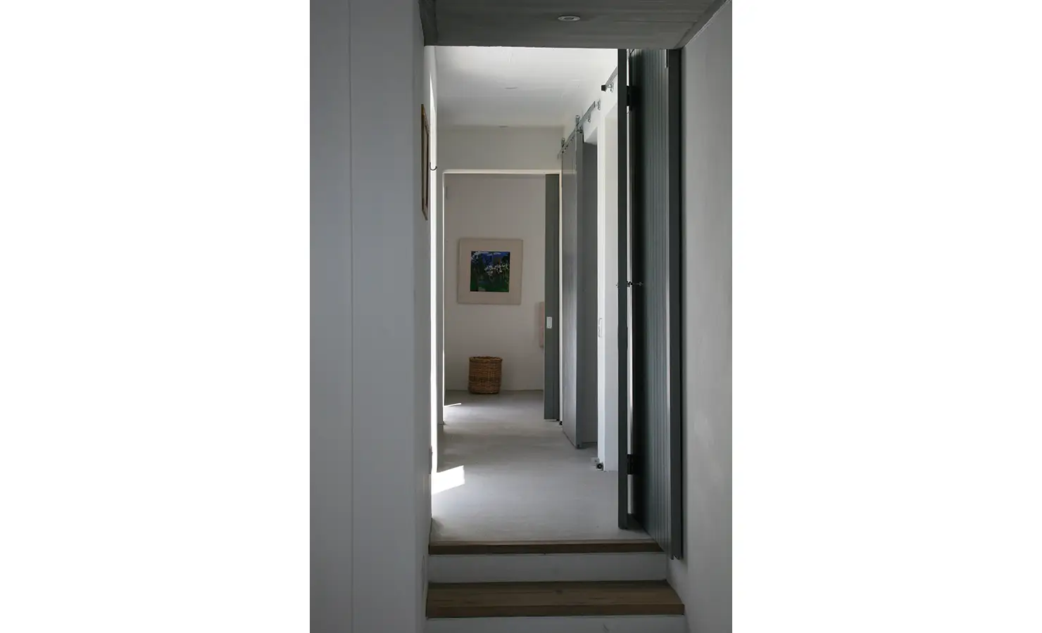 Perfect Hideaways: A sleek, minimalist hallway with clean lines and subtle lighting, leading towards a softly lit room with modern coastal decor. Blue Lagoon, Langebaan.