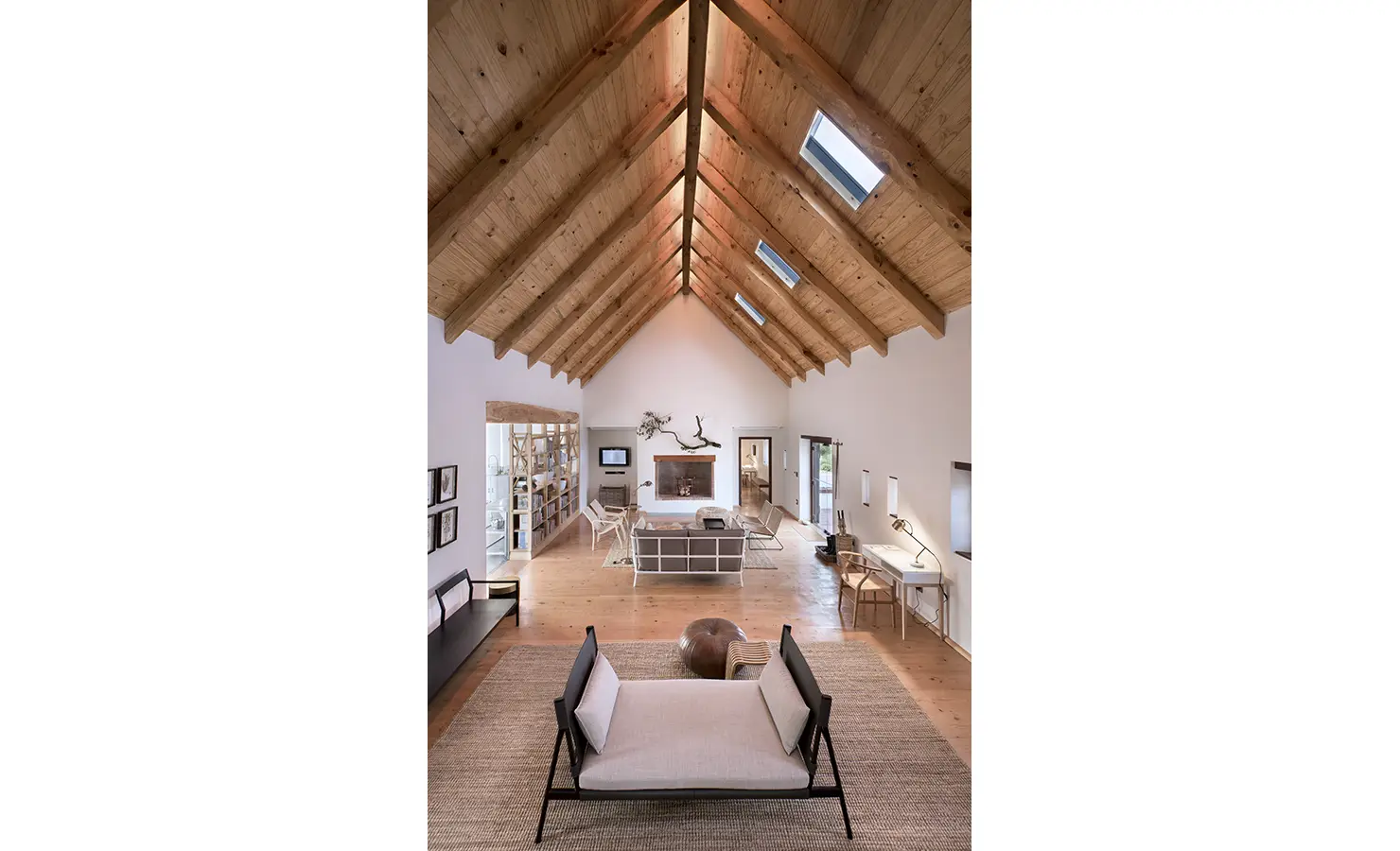 Perfect Hideaways: A grand, open-plan living area with a pitched wooden ceiling, stylish contemporary furniture, and a welcoming fireplace as the focal point. Babylonstoren, Franschhoek.