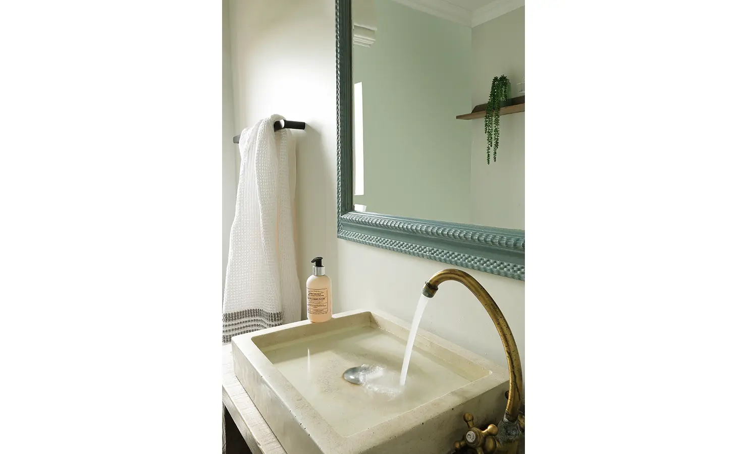 Perfect Hideaways: A rustic bathroom basin with a vintage brass tap flows gently into a stone sink beneath a textured blue-framed mirror. Churchhaven, Fynbos.