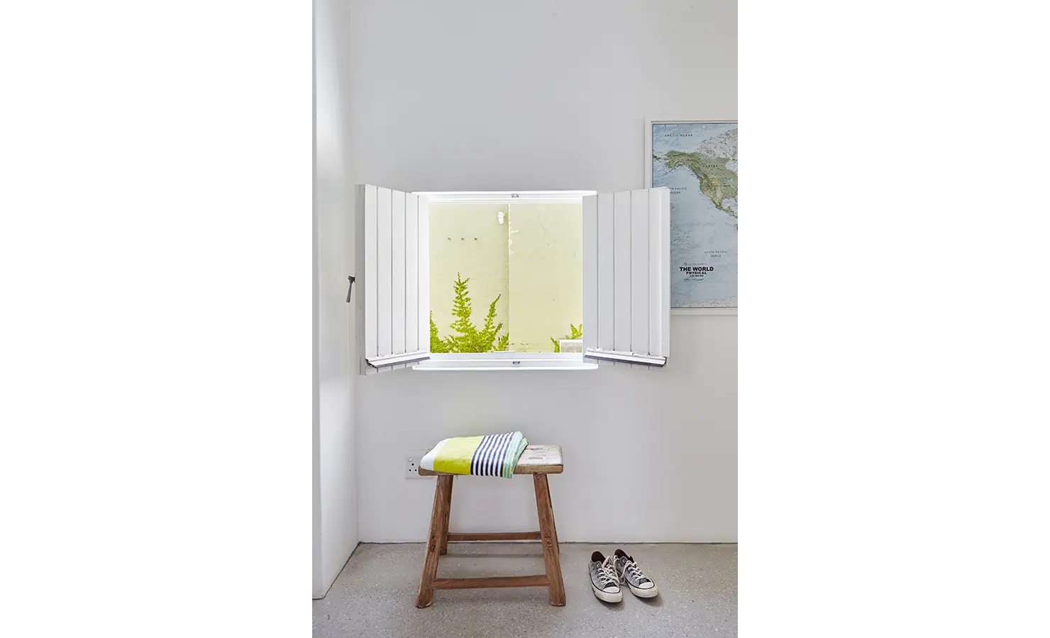 Perfect Hideaways: A charming corner with an open wooden shutter, a rustic stool, and a map of the world, inviting a sense of adventure and relaxation. Blue Lagoon, Langebaan.