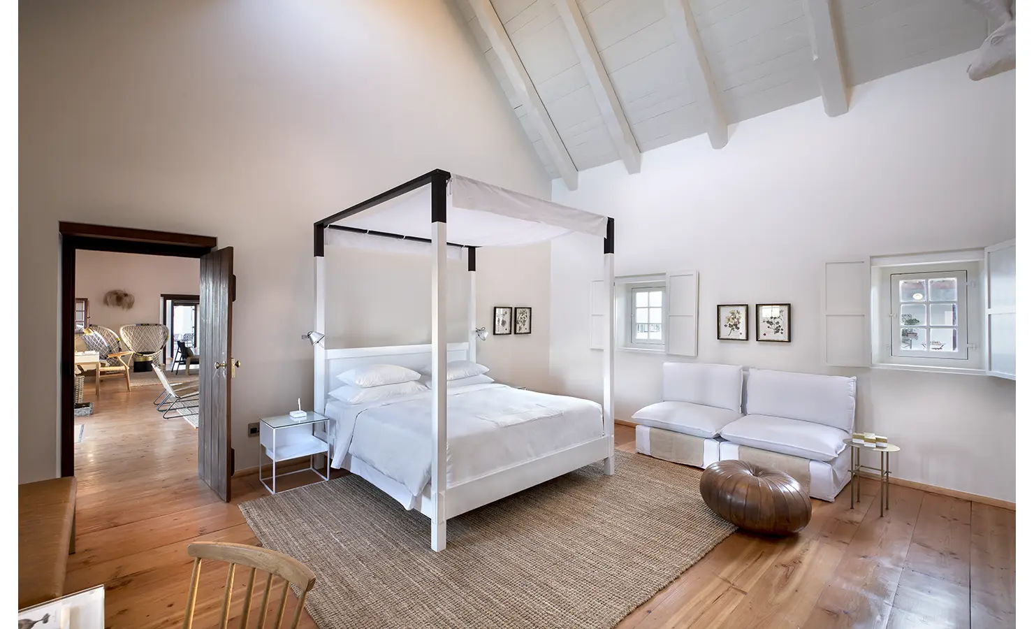 Perfect Hideaways: A bright and airy bedroom featuring a four-poster bed, soft white furnishings, and charming botanical artwork on the walls. Babylonstoren, Franschhoek.