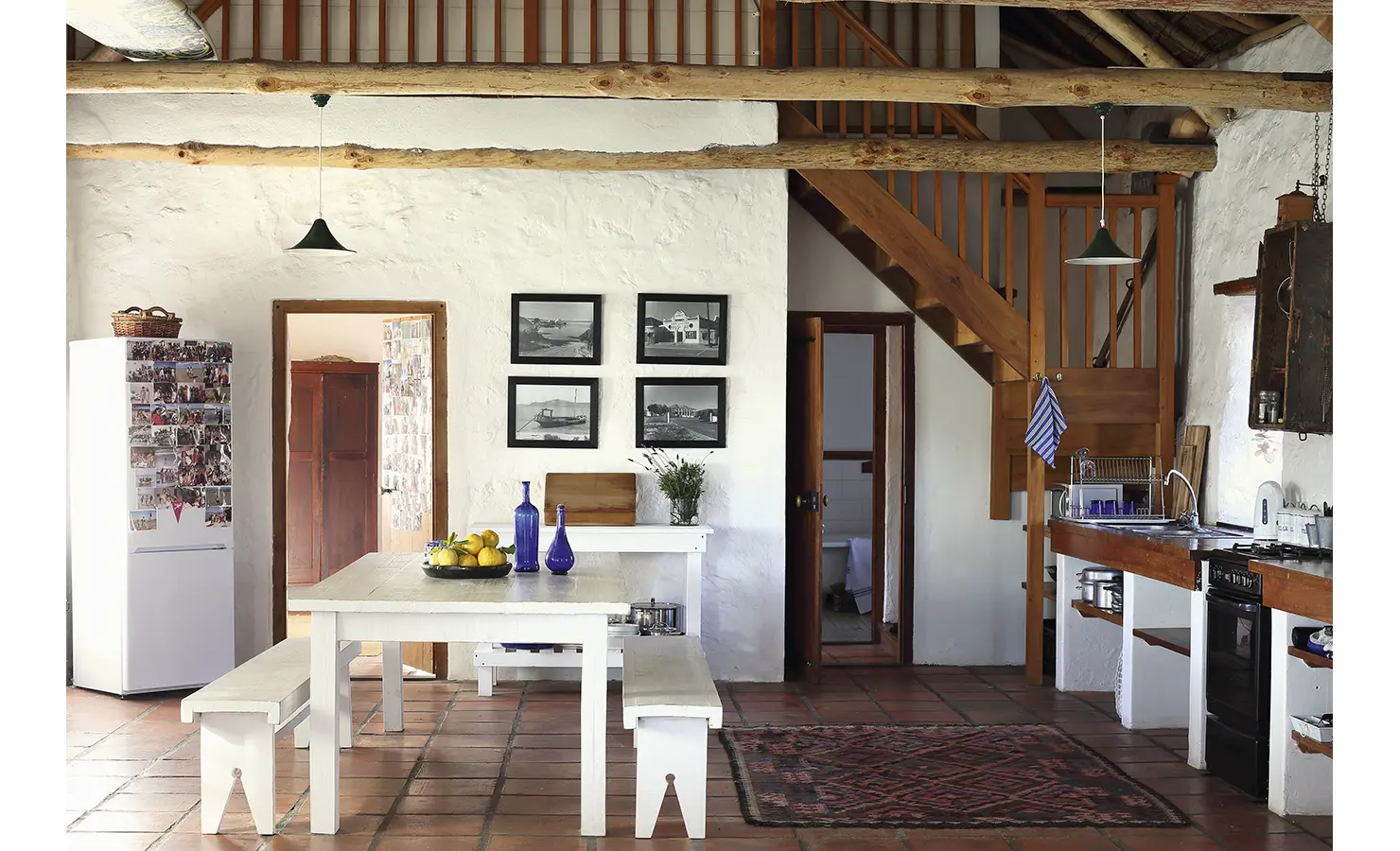 Perfect Hideaways: A rustic farmhouse-style kitchen with a high thatched ceiling, wooden beams, and a cosy dining area. Whitewashed walls, a wooden staircase, and vintage decor create a welcoming and relaxed atmosphere. Panorama, Langebaan.