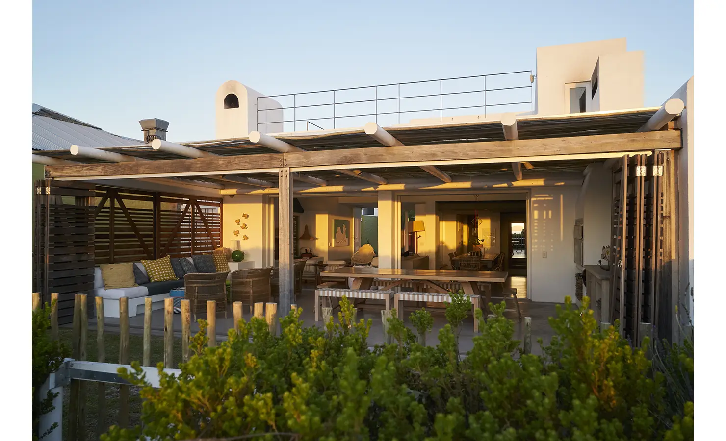 Perfect Hideaways: A stunning outdoor living space bathed in golden sunset light, with a rustic pergola, inviting seating, and a rooftop terrace for panoramic views. Blue Lagoon, Langebaan.
