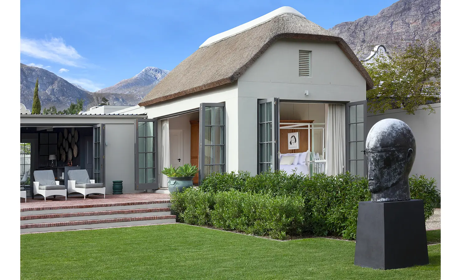 Open plan thatch cottage leading out to patio and garden with mountain backdrop. Koko House.