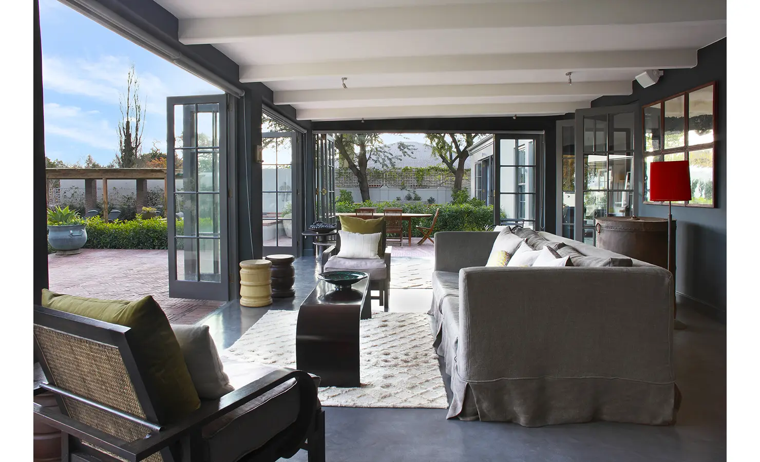 Open plan indoor outdoor lounge area leading out to patio with stacking doors. Koko House.