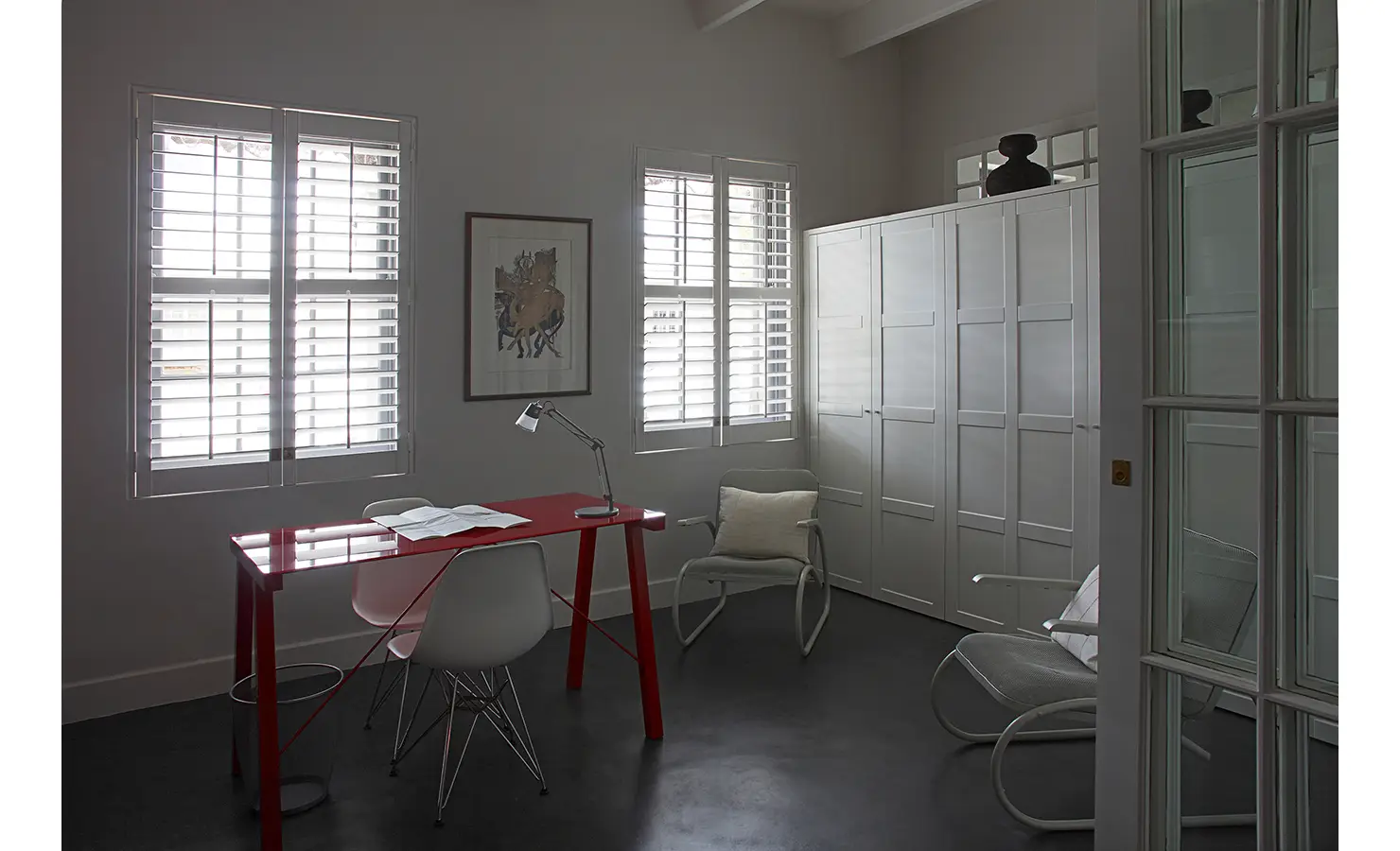 Bright red office desk with white walls, white chairs and white shutters. Koko House.