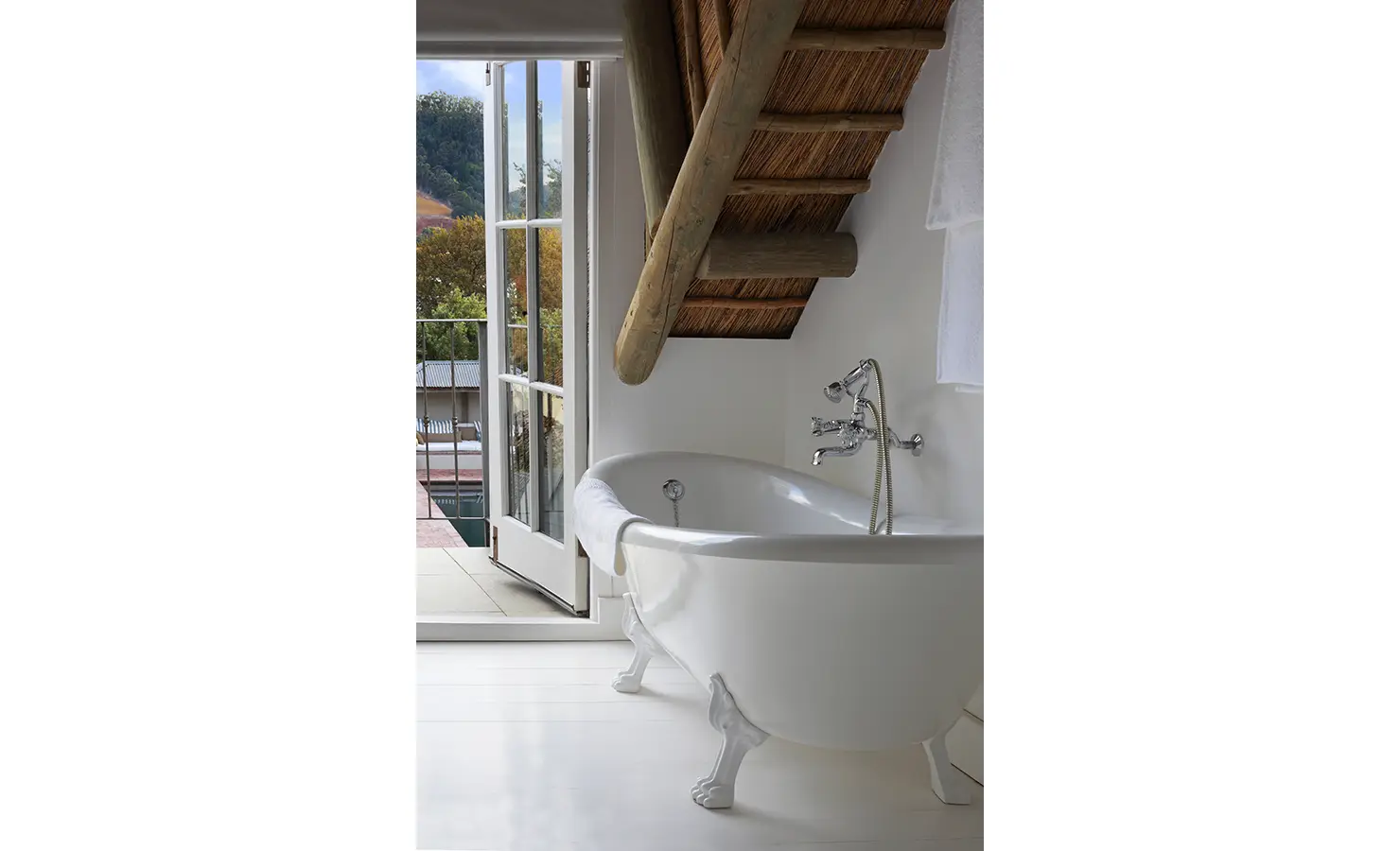 Free standing bath with thatch ceiling overlooking pool area. Koko House.