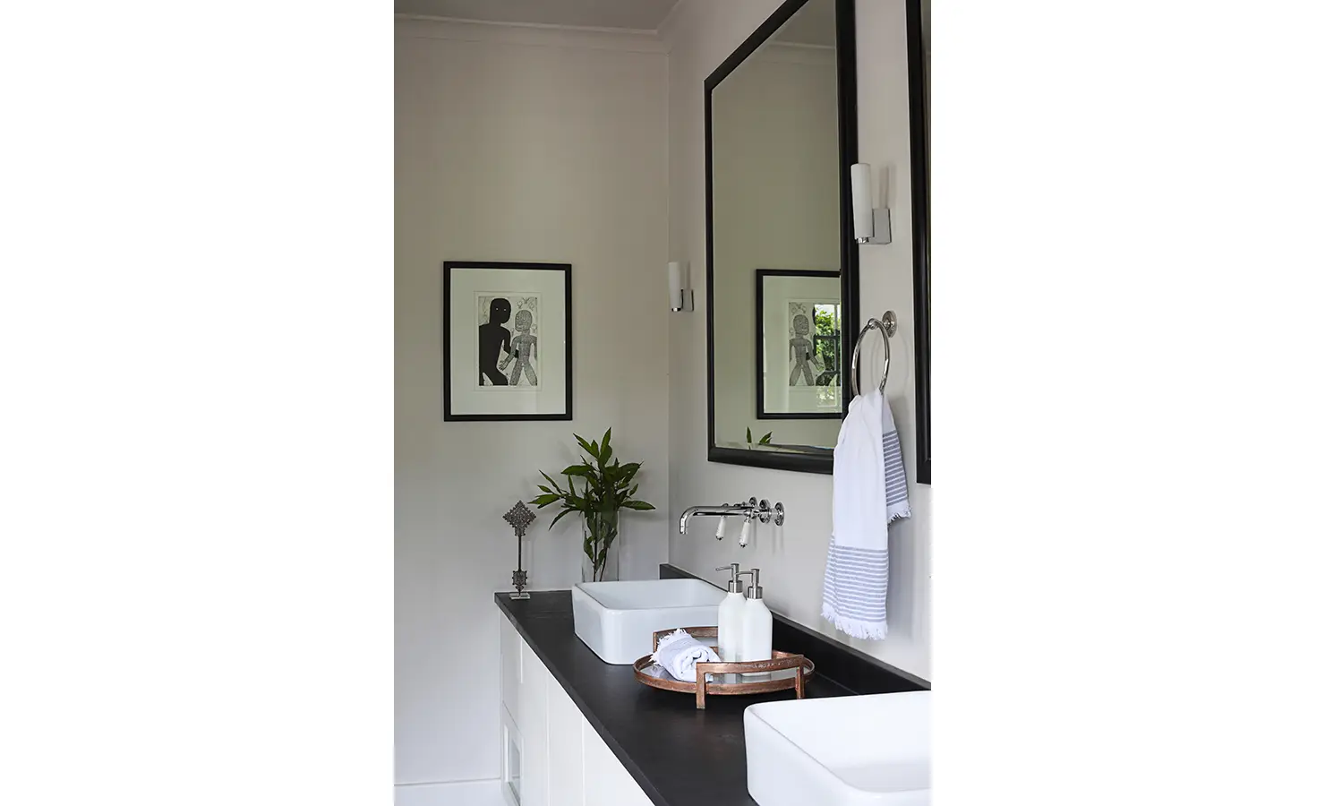 Hand wash basin with large mirror, bathroom accessories and black and white print. Koko House.