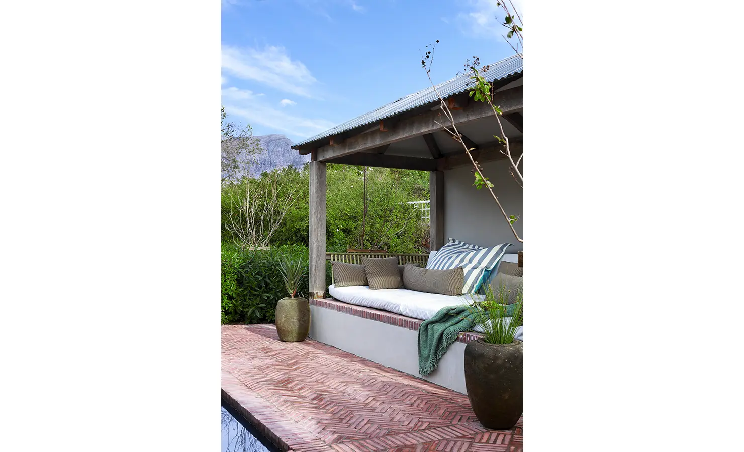 Close up of outdoor pool pergola with backdrop of trees, mountains and clear skies. Koko House.