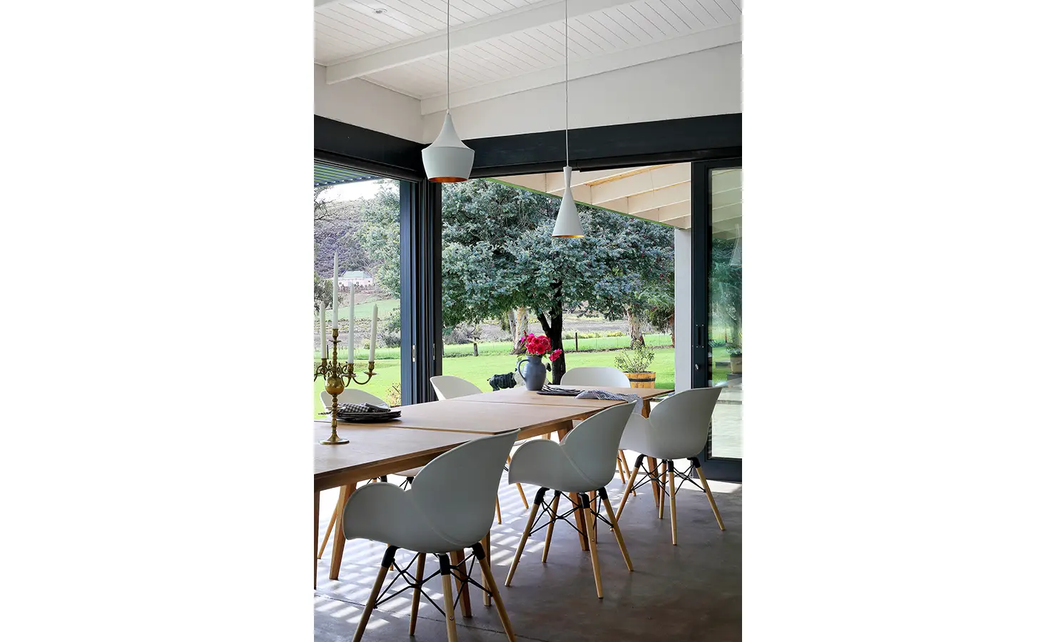 Perfect Hideaways: The dining space opens seamlessly to the outdoors through glass doors, offering tranquil garden views and dappled light beneath the shelter of the patio roof. 22 Degrees East, Prince Albert.