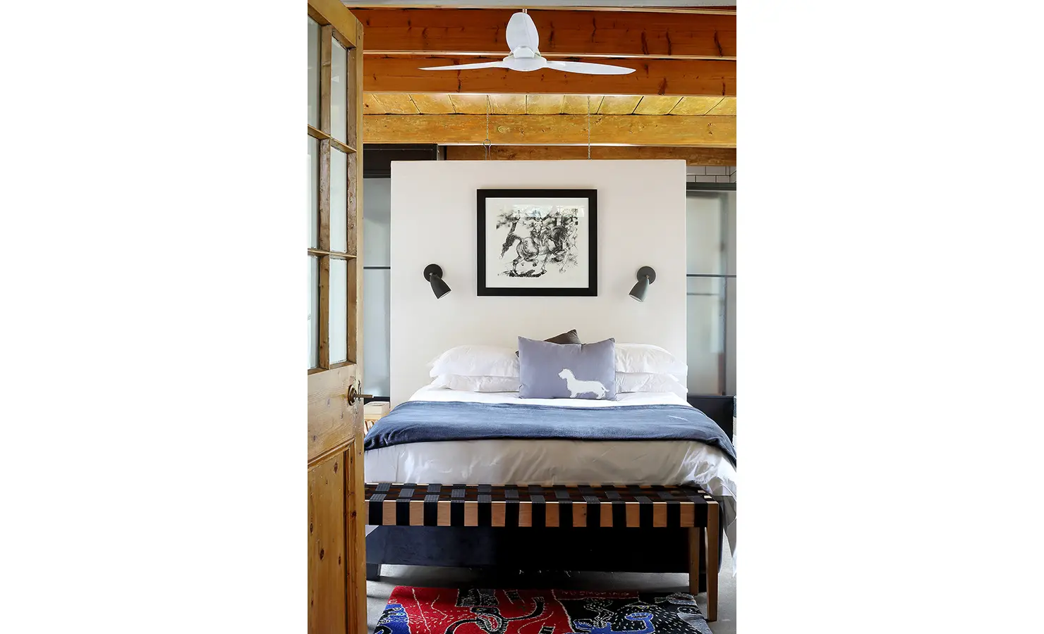 Perfect Hideaways: A stylish bedroom with exposed beams and natural wood features a neutral palette, monochrome artwork, and clever spatial design with a floating partition wall. 22 Degrees East, Prince Albert.