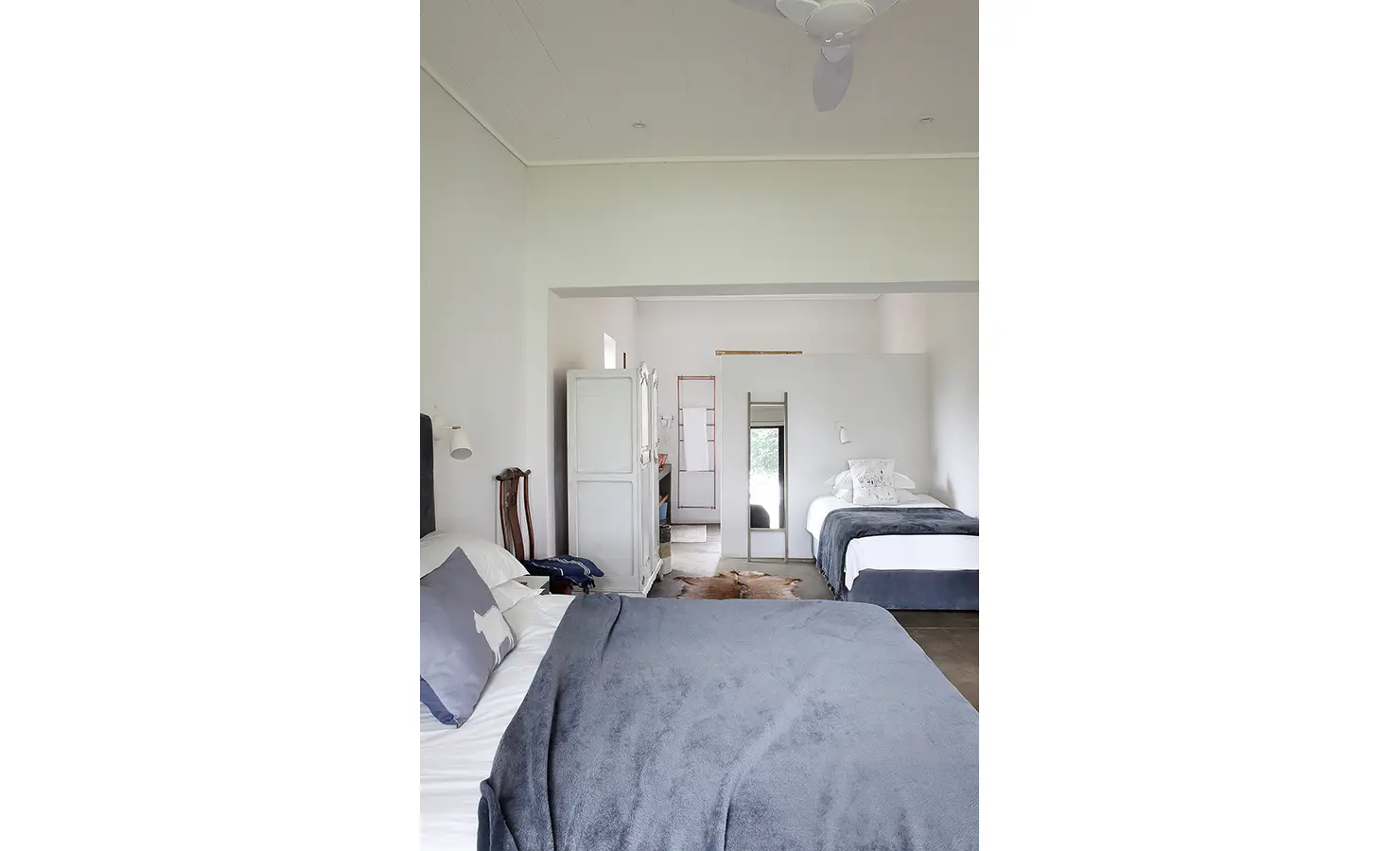 Perfect Hideaways: A spacious, open-plan bedroom with clean white walls and layered grey bed linens includes both a double and single bed, perfect for family stays. 22 Degrees East, Prince Albert.
