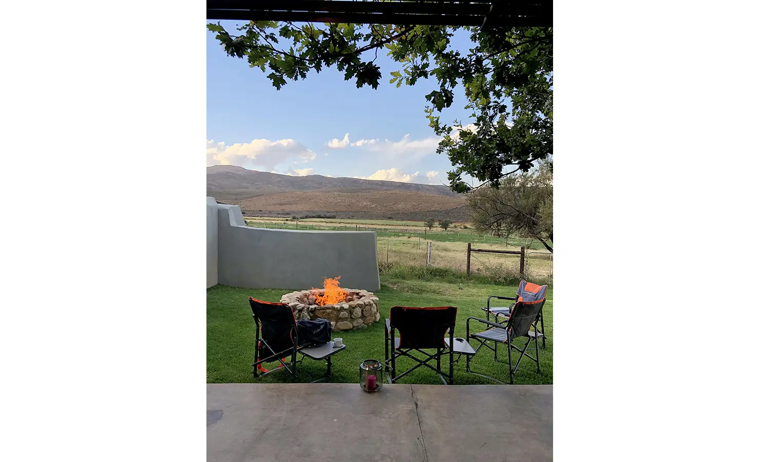 Perfect Hideaways: A cosy outdoor fire pit with camping chairs set on a lawn invites guests to unwind as the sun sets over the Karoo hills. 22 Degrees East, Prince Albert.