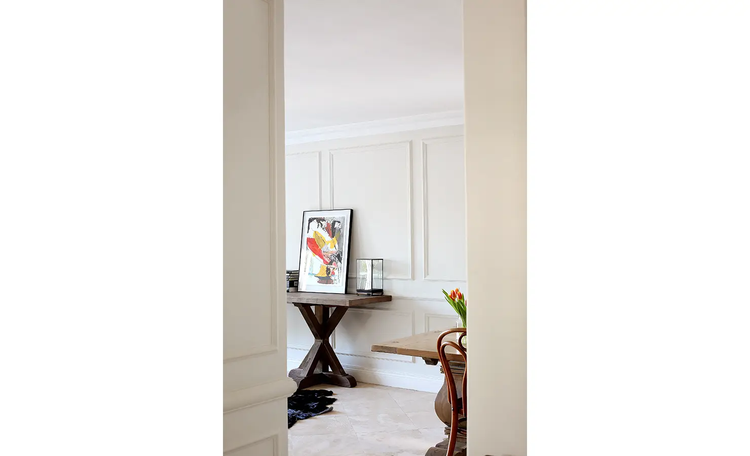 Perfect Hideaways: A peek into a stylish corner of the home where a bold abstract artwork rests on a wooden pedestal table beside natural textures and neutral tones. Pepper Tree House, De Waterkant.