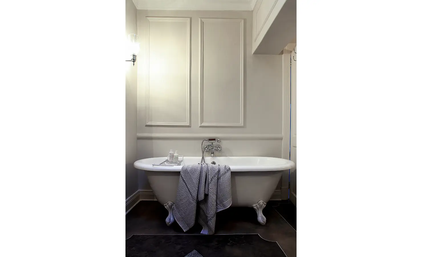 Perfect Hideaways: Freestanding clawfoot bathtub set against pale panelled walls, with soft towels and bath amenities arranged for a serene soak. Pepper Tree House, De Waterkant.