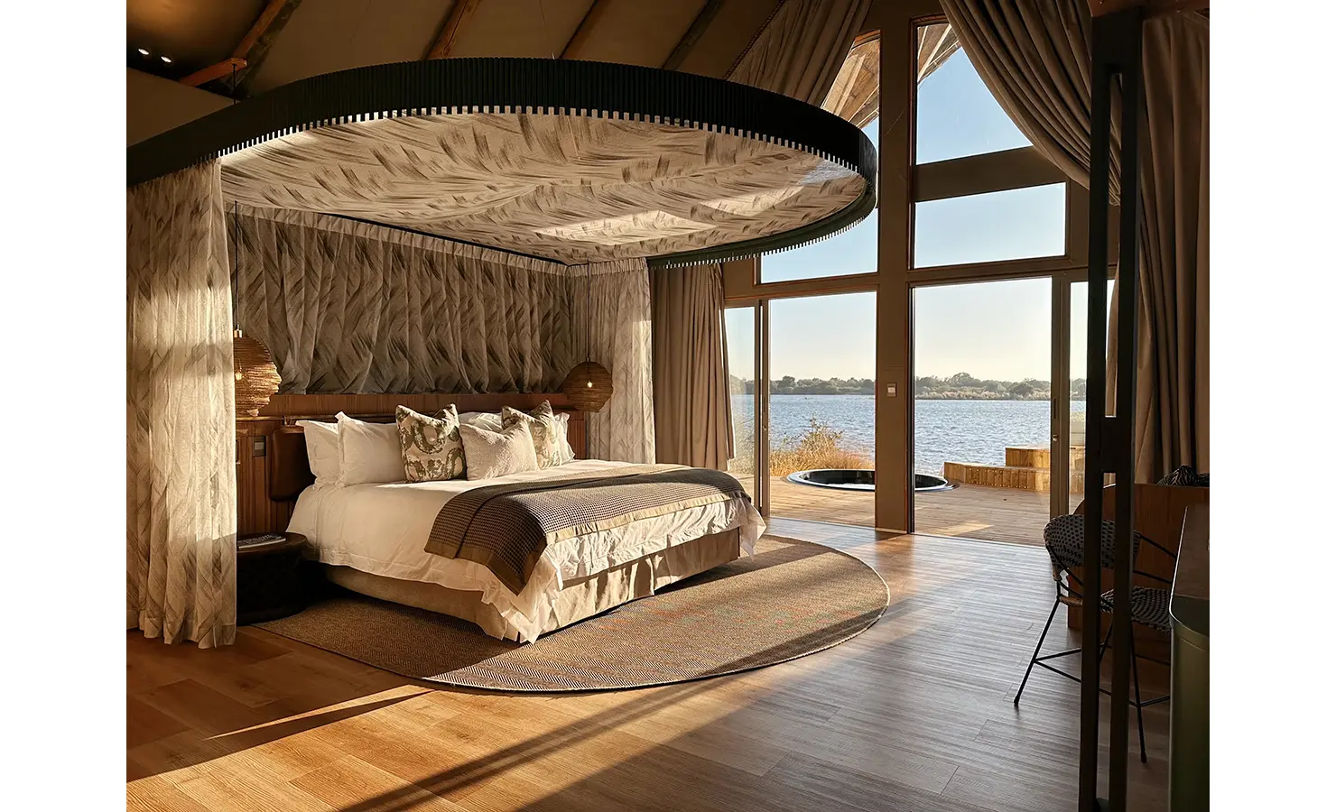 Perfect Hideaways: A breathtaking safari suite with floor-to-ceiling windows, a statement ceiling design, and a plush king-size bed, opening onto a private deck with a plunge pool overlooking the Zambezi River. Victoria Falls River Lodge, Zambezi National Park.