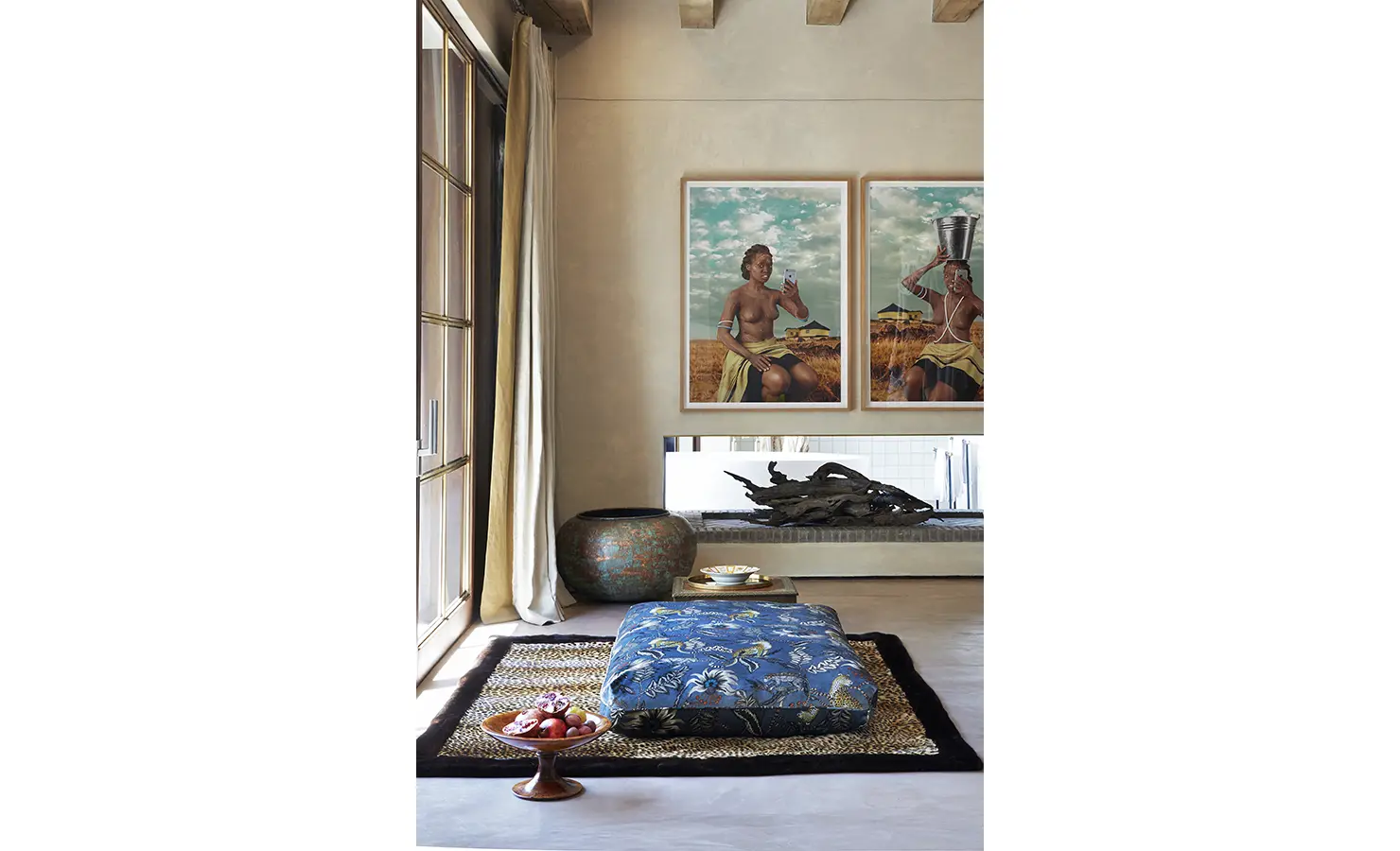 Perfect Hideaways: A serene corner adorned with vibrant wall art, a low upholstered seat with botanical patterns, and decorative items such as a wooden bowl and a ceramic vase. Kubili House, Thornybush Game Reserve.