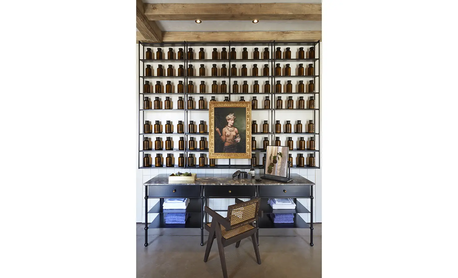 Perfect Hideaways: A stylish interior displaying shelves filled with amber glass bottles, a marble-topped desk, and a framed portrait in the centre. Kubili House, Thornybush Game Reserve.