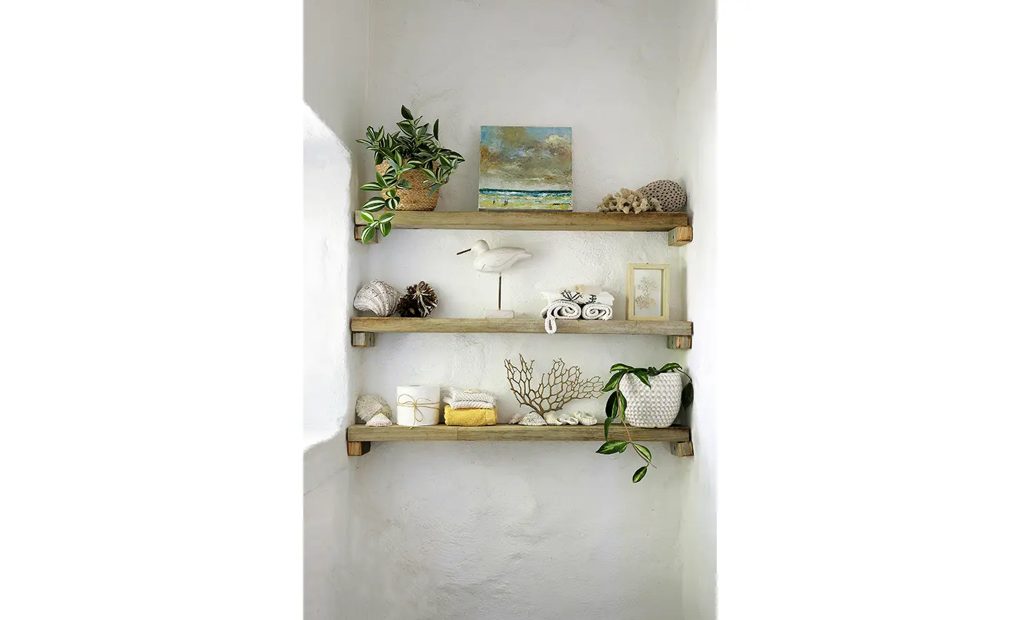 Perfect Hideaways: Shelves styled with beach-inspired decor, including shells, coral, small potted plants, and a framed painting of the ocean. Farniente, Kommetjie.