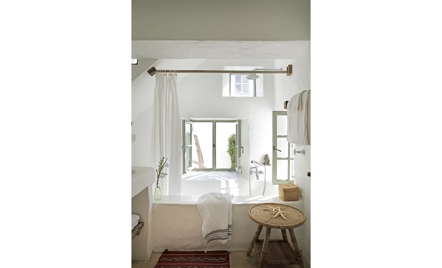 Perfect Hideaways: A light-filled bathroom featuring a soaking tub with white curtains, rustic accents, and an open window looking out onto greenery. Farniente, Kommetjie.