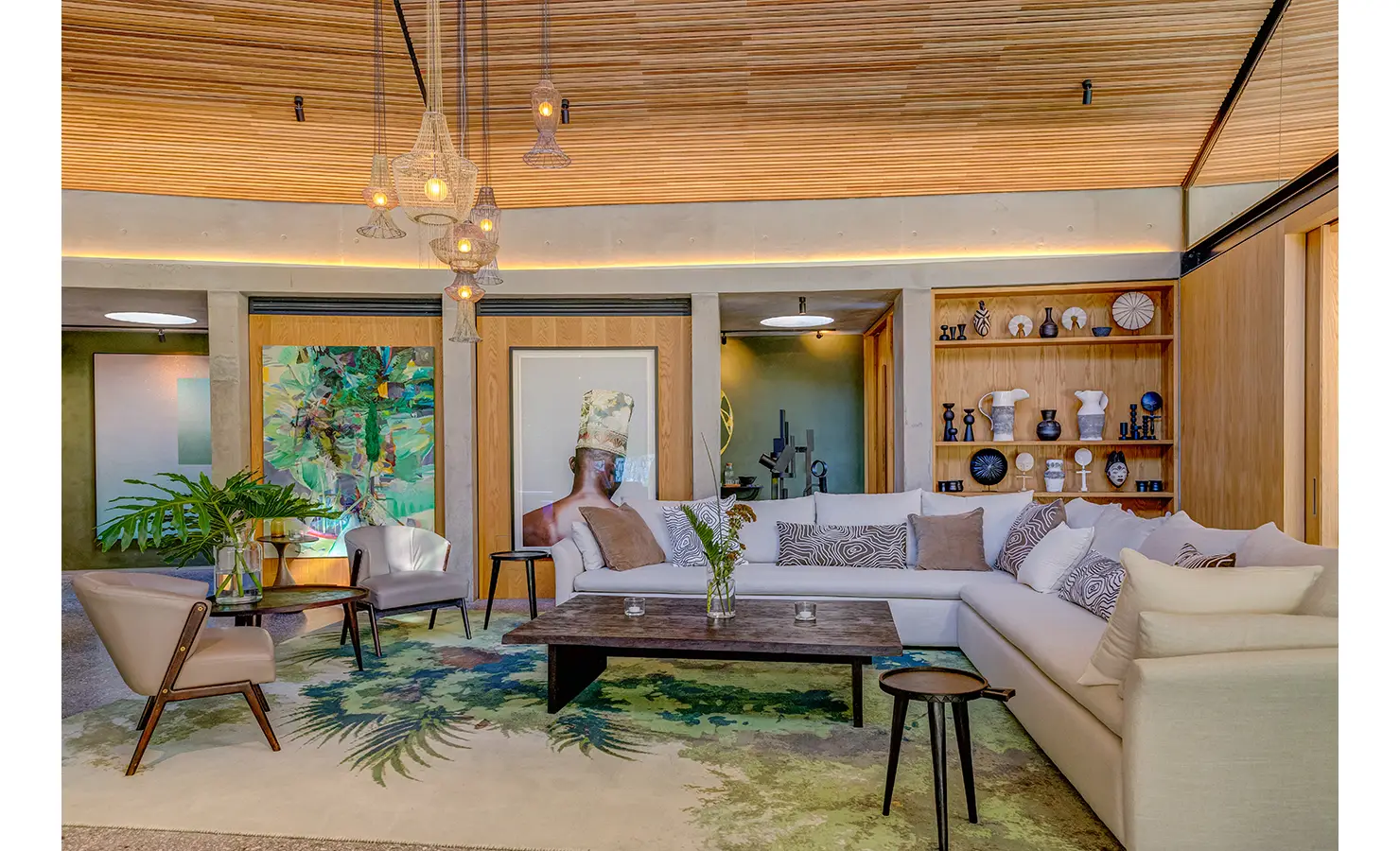 Perfect Hideaways: A stylish lounge with a neutral palette, contemporary artwork, and a curated display shelf, brought together by soft lighting and a nature-inspired rug for a warm, artistic atmosphere. Villa Verte, Hout Bay.