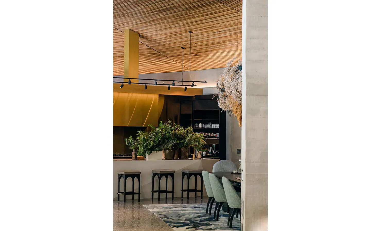Perfect Hideaways: A partial view of the open-plan kitchen and dining area, showing rich textures, architectural detail, and natural materials blending luxury with organic form. Villa Verte, Hout Bay.