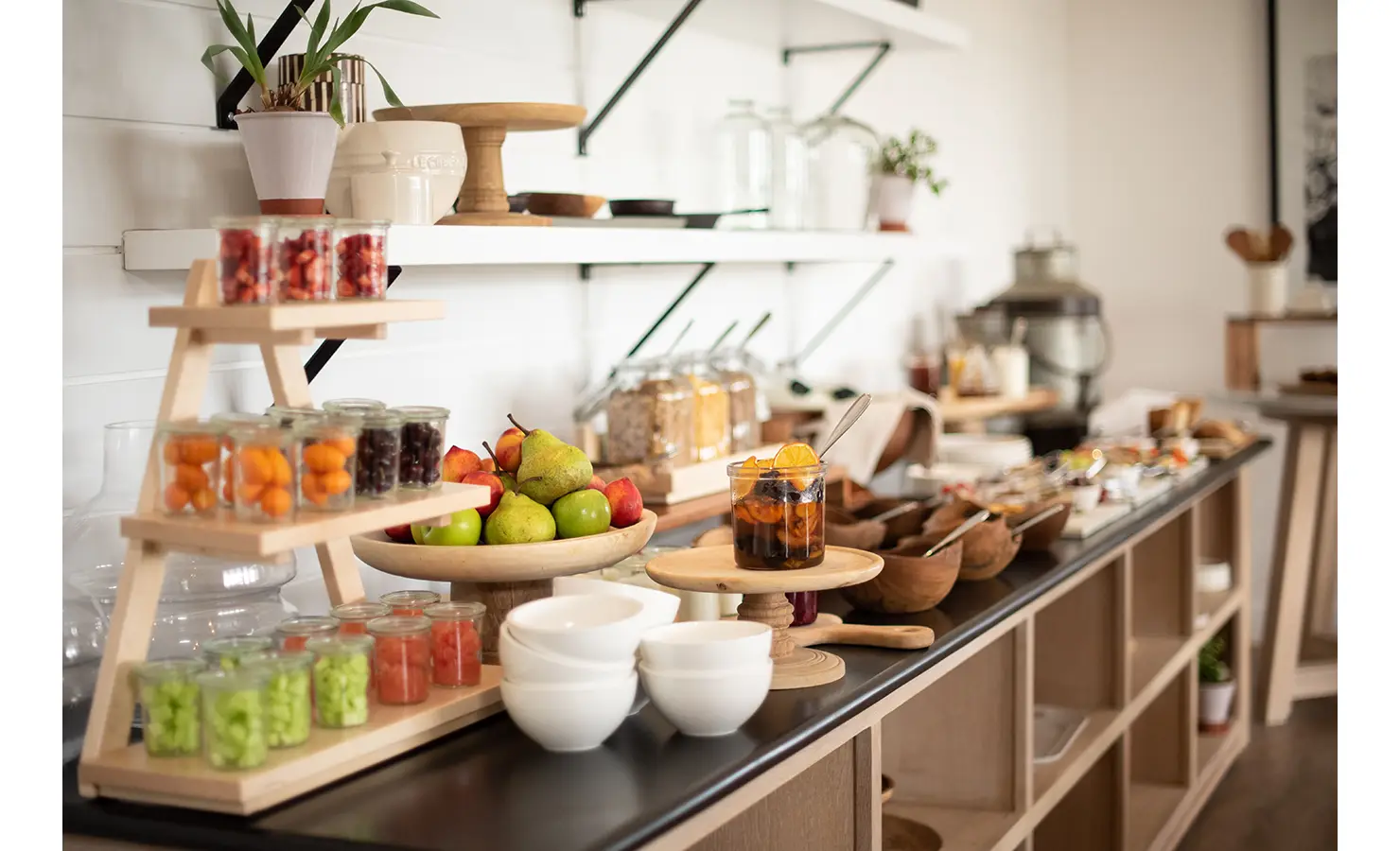 Perfect Hideaways: A buffet table showcasing a vibrant array of fresh fruits, cereals, and preserves in glass jars, with wooden accents. Riverdene, Shamwari Private Game Reserve.