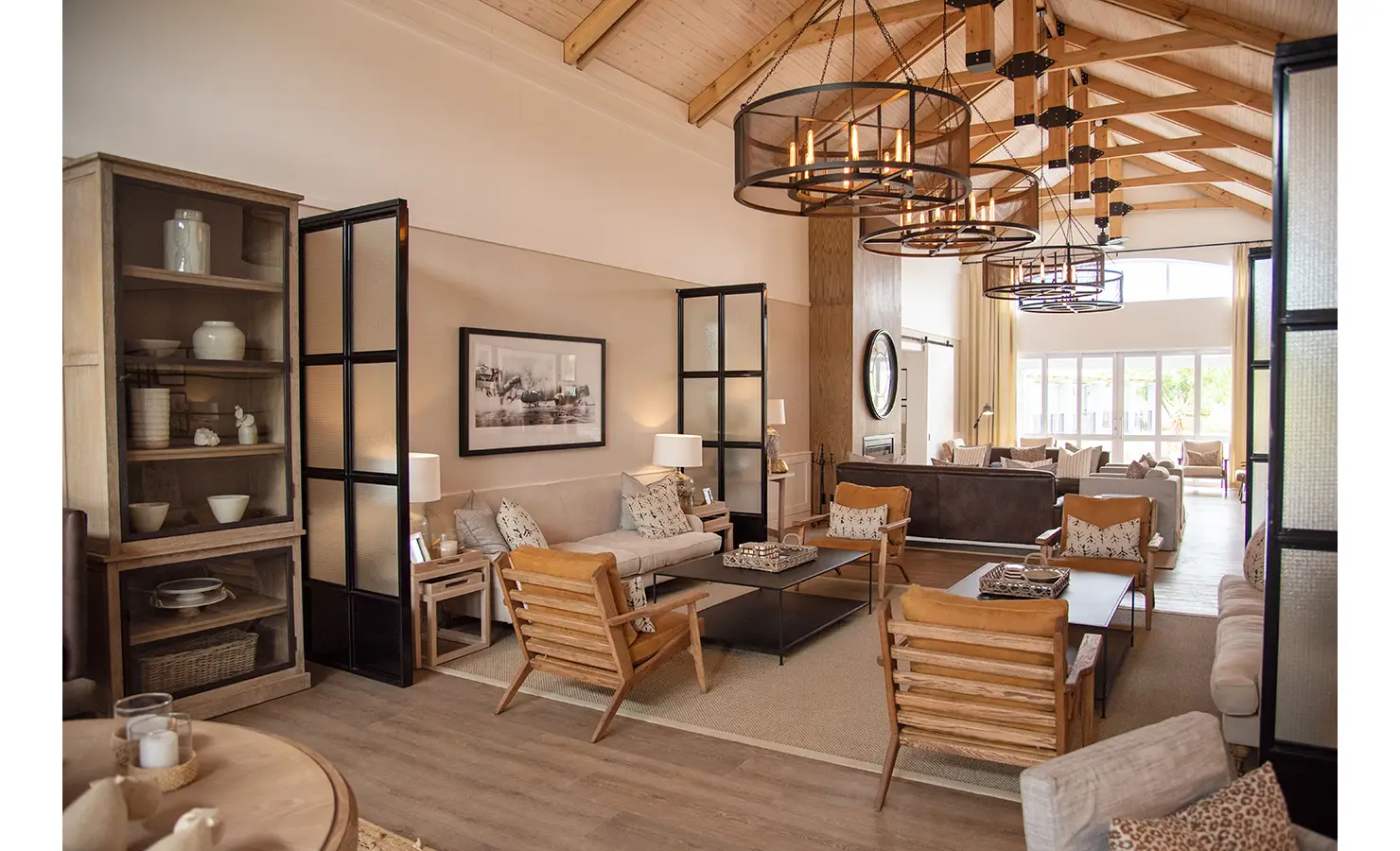 Perfect Hideaways: A warm and inviting lounge area with comfortable seating, rustic wooden decor, and large windows allowing natural light. Riverdene, Shamwari Private Game Reserve.