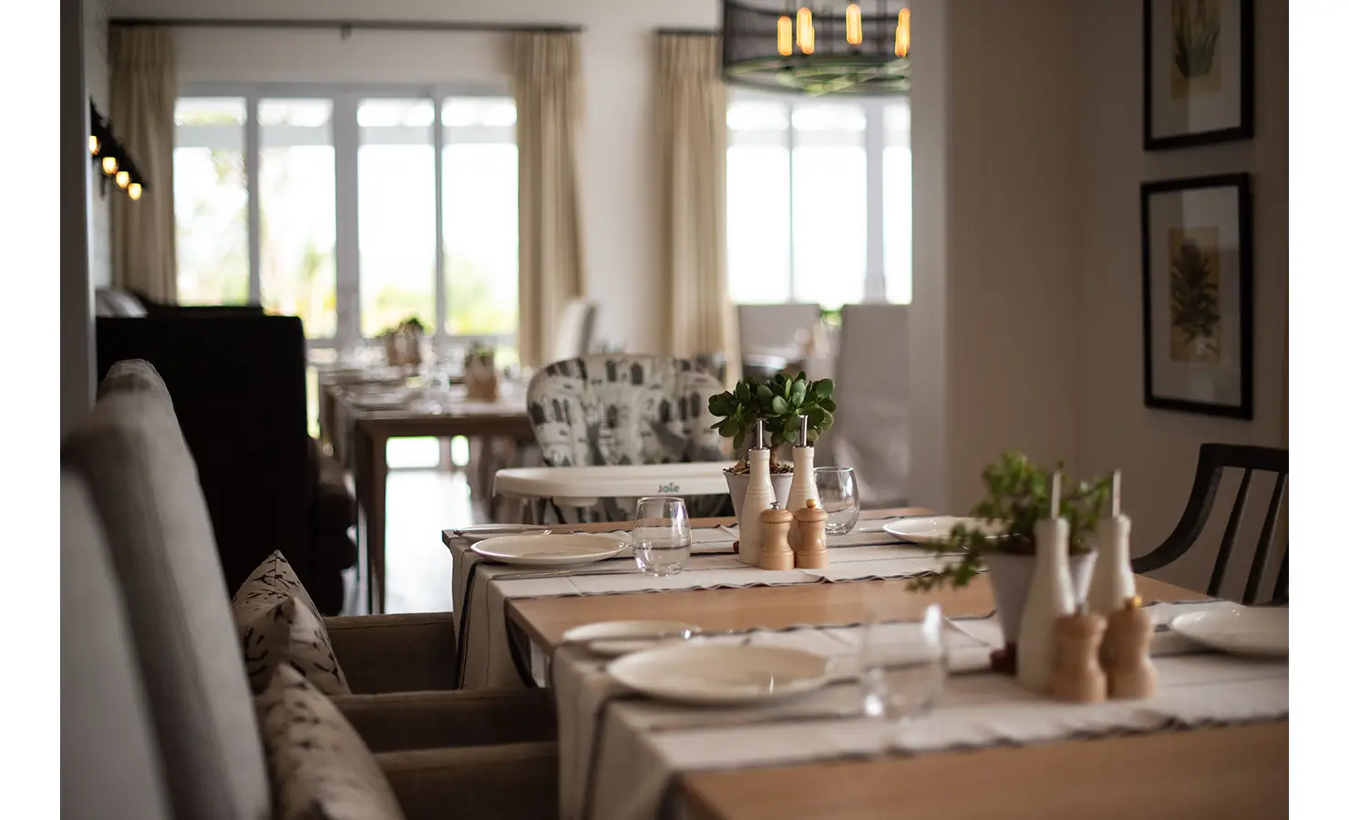 Perfect Hideaways: A dining area with neatly set tables adorned with greenery and soft lighting, offering a warm and inviting atmosphere. Riverdene, Shamwari Private Game Reserve.