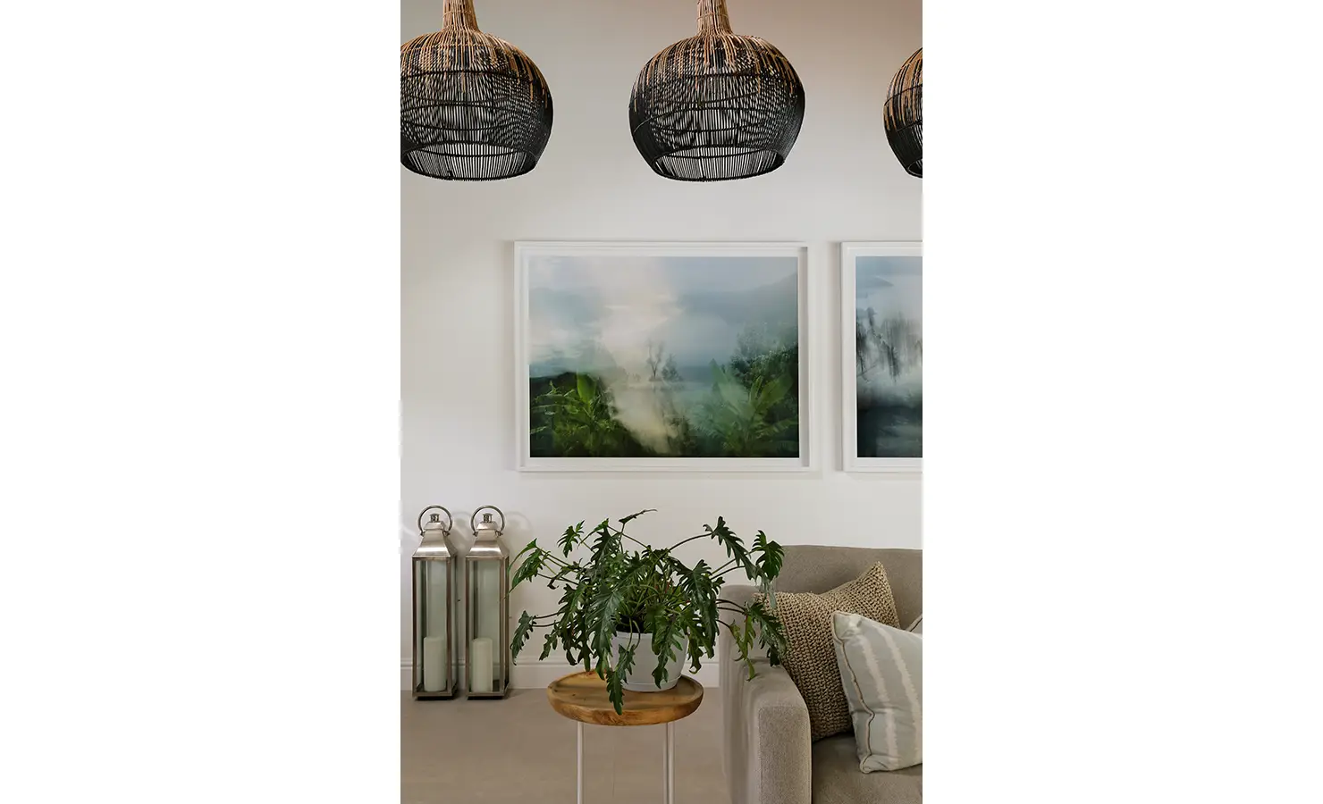 Perfect Hideaways: A stylish interior with black woven pendant lights, misty landscape artwork, a neutral-toned sofa, and lush greenery adding a touch of freshness. Buitenzorg Estate, Constantia.