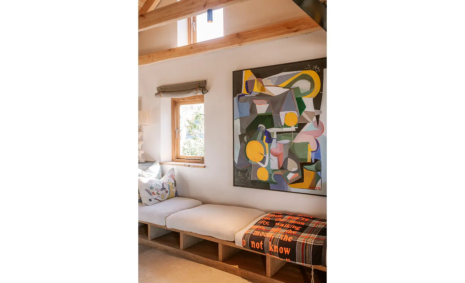 Perfect Hideaways: A serene reading nook under exposed timber beams features a built-in cushioned bench, playful throw pillows and a colourful abstract painting that brings vibrancy to the sunlit space. Yellowwood Cottage, Churchhaven.