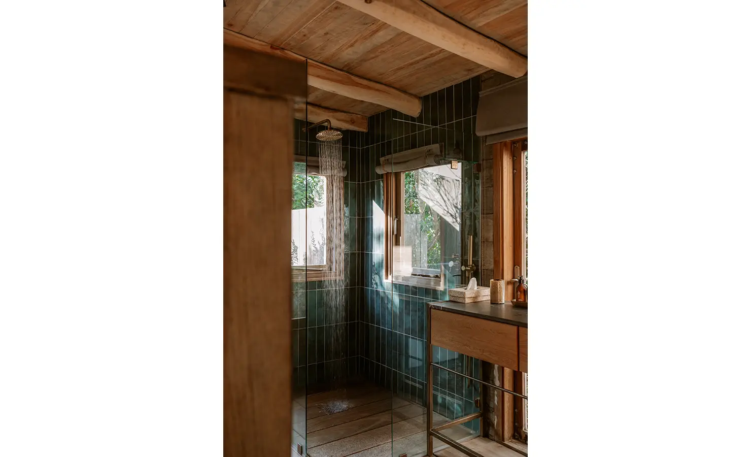 Perfect Hideaways: A luxurious bathroom with forest-green tiled walls, exposed beams and large windows, features a glass-enclosed shower and minimalist stone vanity, blending elegance with nature. Yellowwood Cottage, Churchhaven.