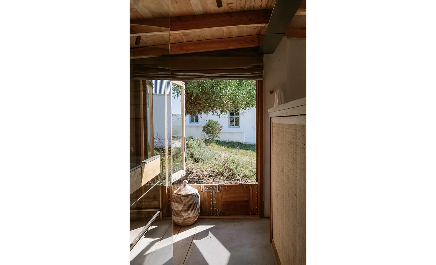 Perfect Hideaways: A quiet bathroom view looking out to the garden, with sunlight streaming through an open stable door. A woven lidded basket rests near a rustic vanity, merging calm utility with soft natural textures. Yellowwood Cottage, Churchhaven.