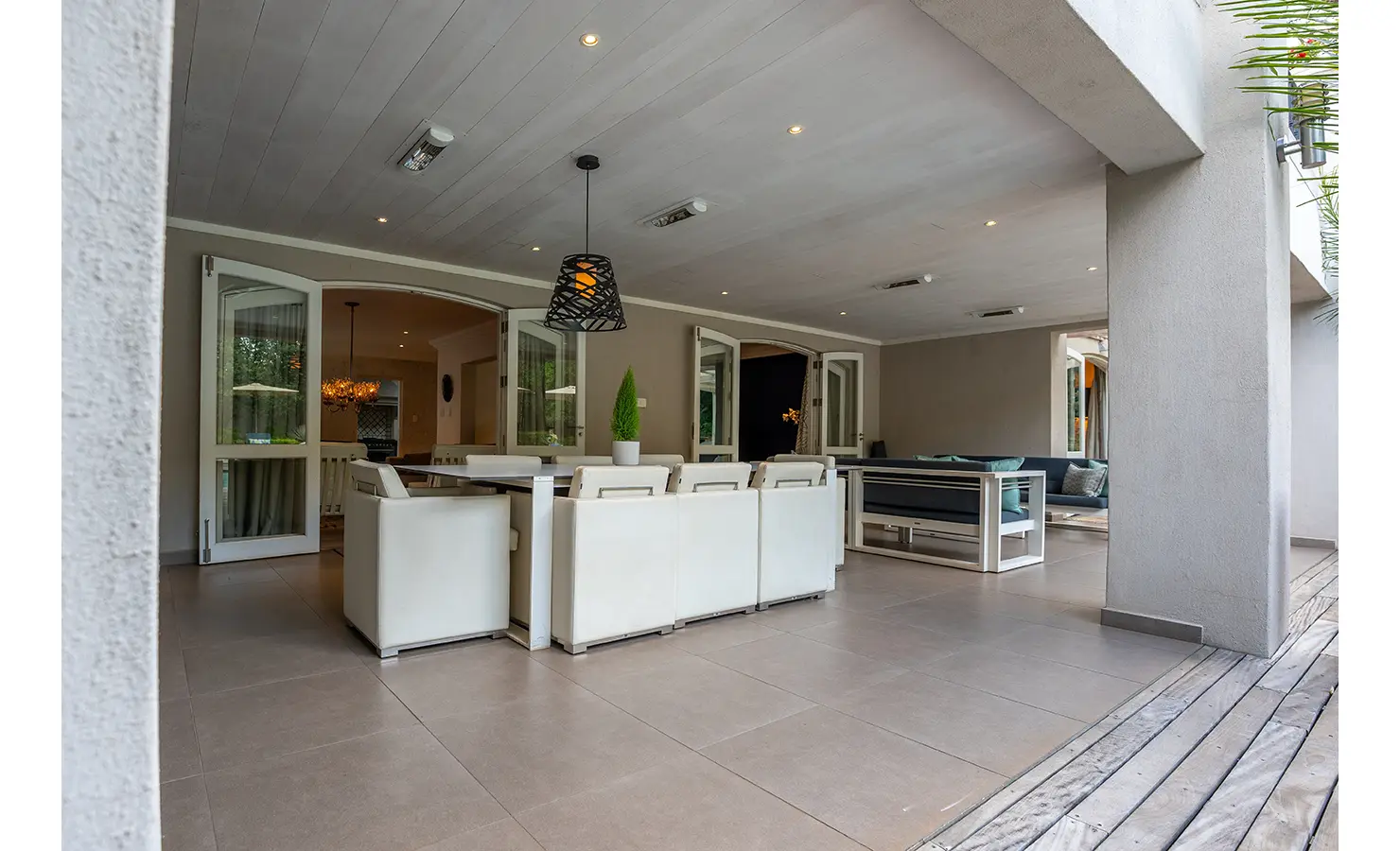 Perfect Hideaways: A shaded patio with modern white furniture opens onto a spacious and stylish outdoor entertainment area, perfect for relaxed al fresco dining. AtholPlace Hotel & Villa, Atholl.