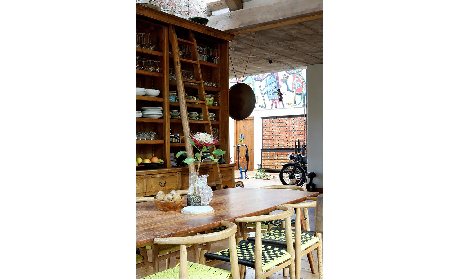 Perfect Hideaways. A rustic wooden table accompanied by bright neon chairs, creating a warm and welcoming atmosphere for gatherings. Gaia, Constantia.