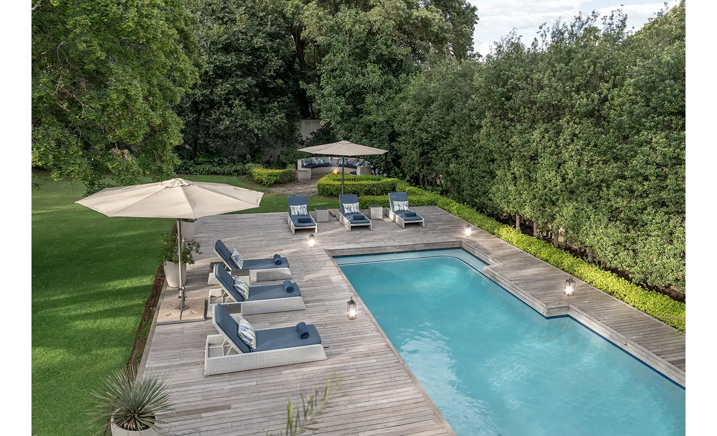 Perfect Hideaways: A pristine swimming pool is surrounded by a wooden deck and navy cushioned loungers, offering a tranquil setting amid lush greenery. AtholPlace Hotel & Villa, Atholl.