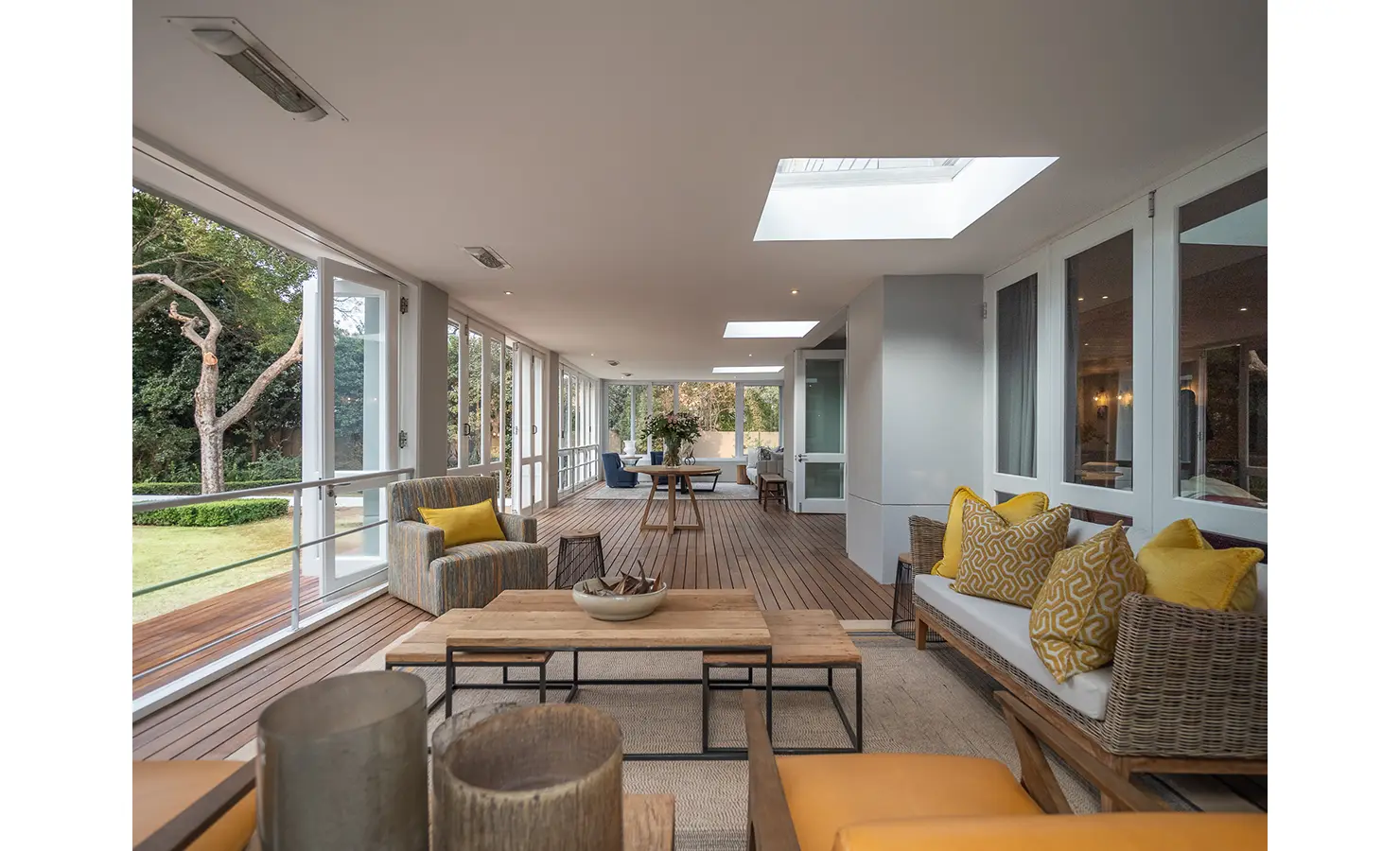 Perfect Hideaways: A light-filled conservatory-style lounge opens to the garden, with wicker seating, warm timber floors, and cheerful yellow accents adding relaxed elegance. AtholPlace Hotel & Villa, Atholl.