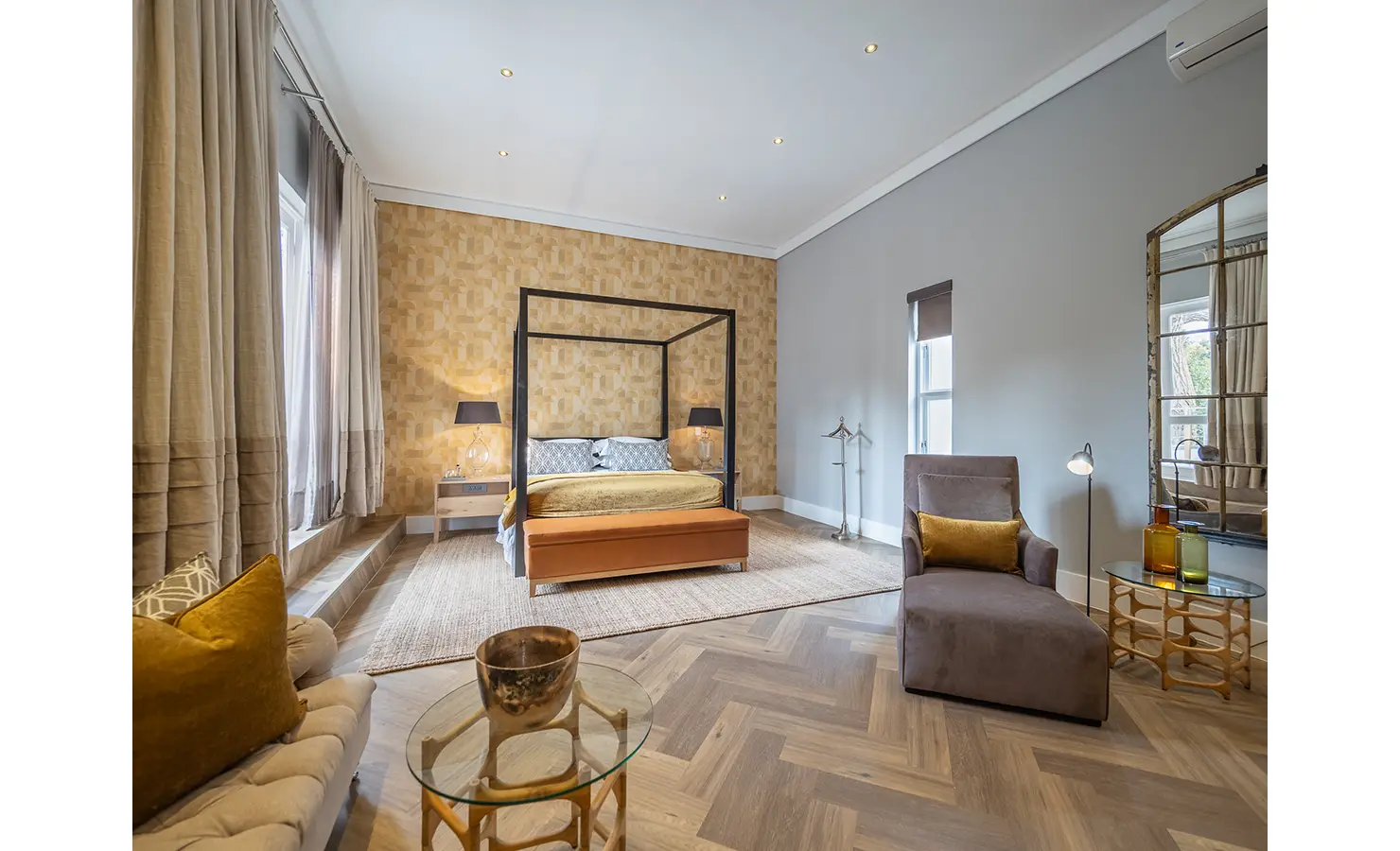 Perfect Hideaways: A spacious bedroom with a four-poster bed, warm golden tones, and elegant parquet floors is styled with velvet seating and refined modern accents. AtholPlace Hotel & Villa, Atholl.