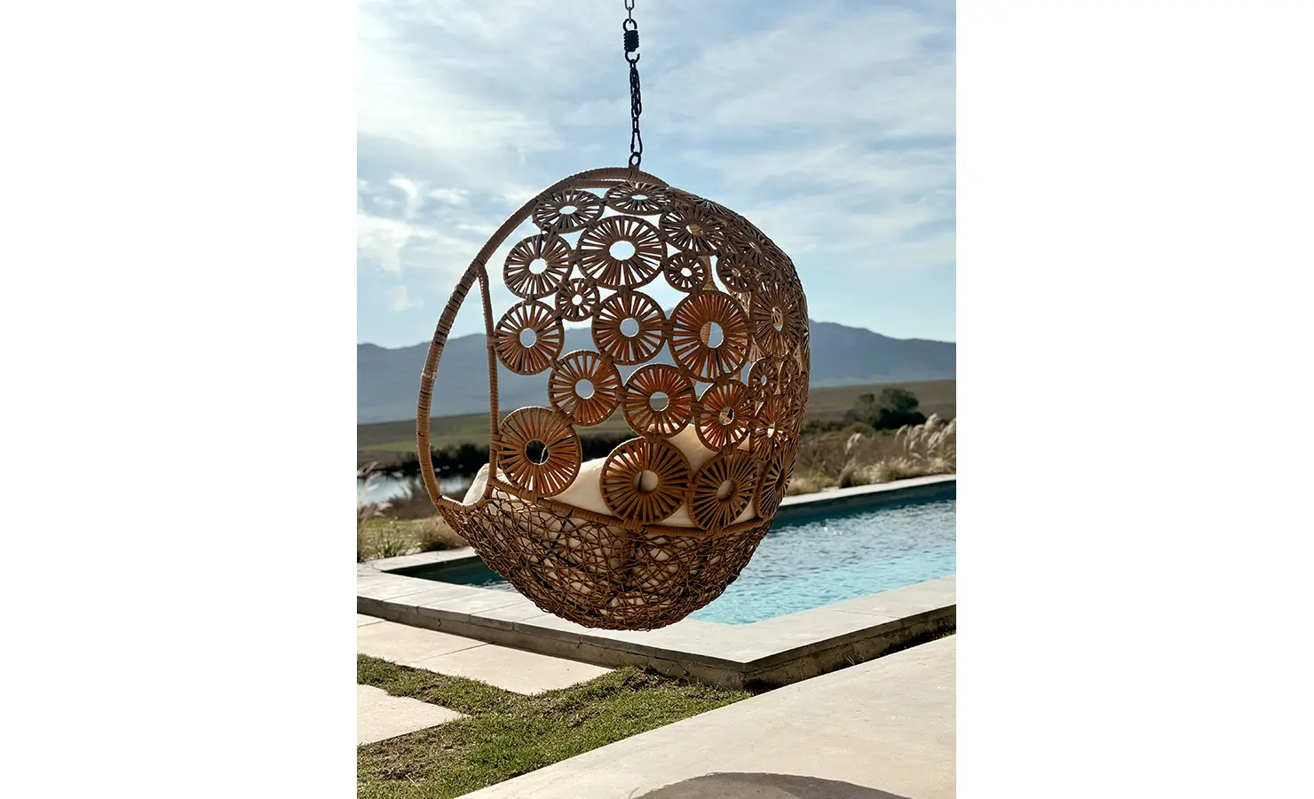 Perfect Hideaways: Decorative hanging wicker chair with intricate floral design overlooking the pool and mountain backdrop, Thuúla Haven, Hemel-en-Aarde.