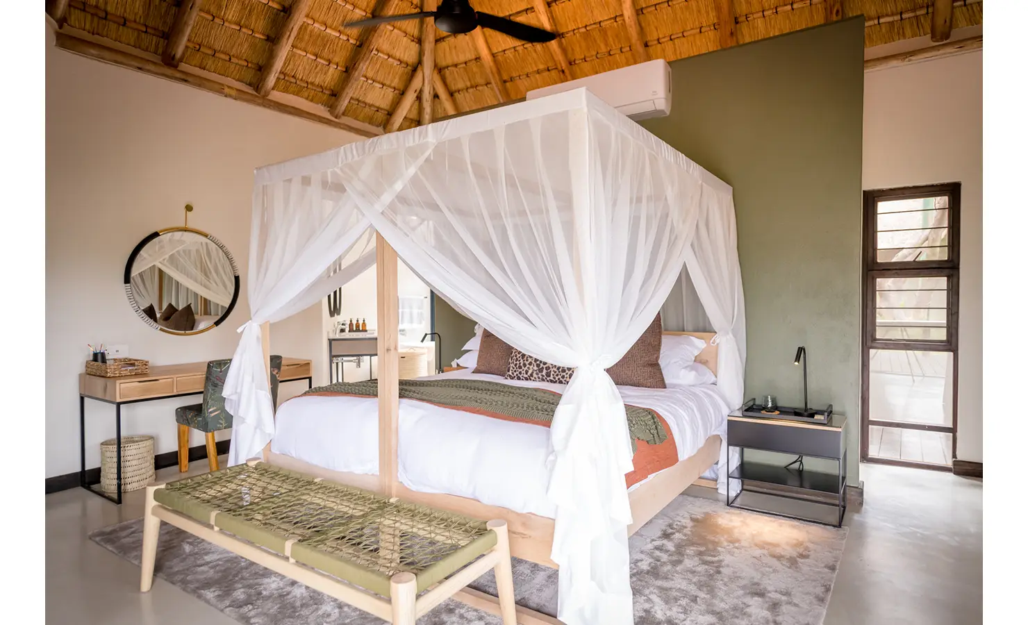 Perfect Hideaways: A beautifully designed bedroom featuring a four-poster bed with a mosquito net canopy, rustic wooden furniture, and elegant décor. Tulela Lodge, Klaserie Private Nature Reserve.