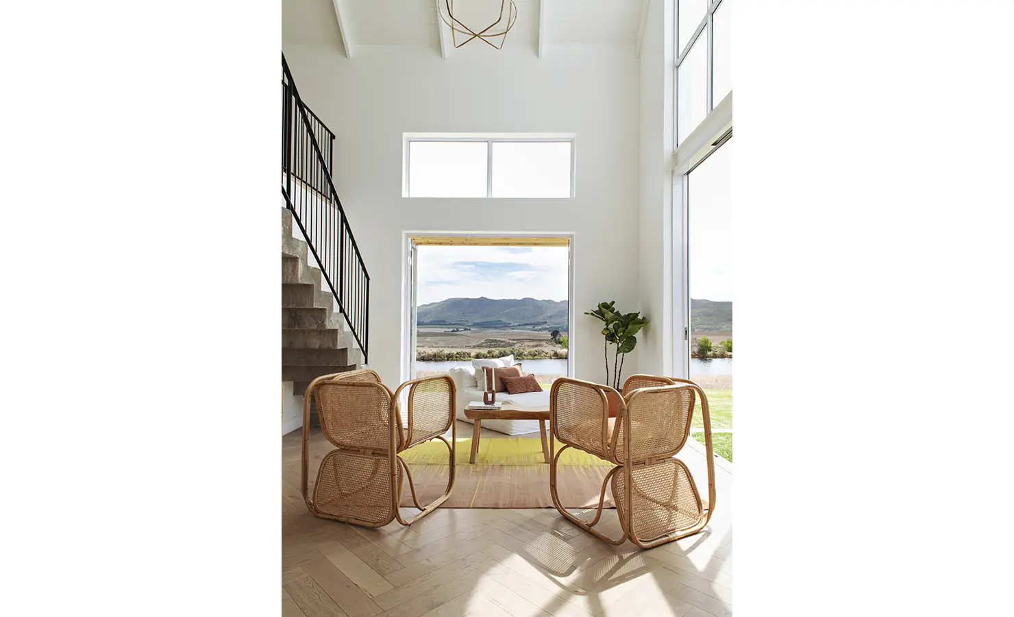 Perfect Hideaways: Double-volume lounge with rattan chairs and full-height windows framing mountain and dam views, Thuúla Haven, Hemel-en-Aarde.