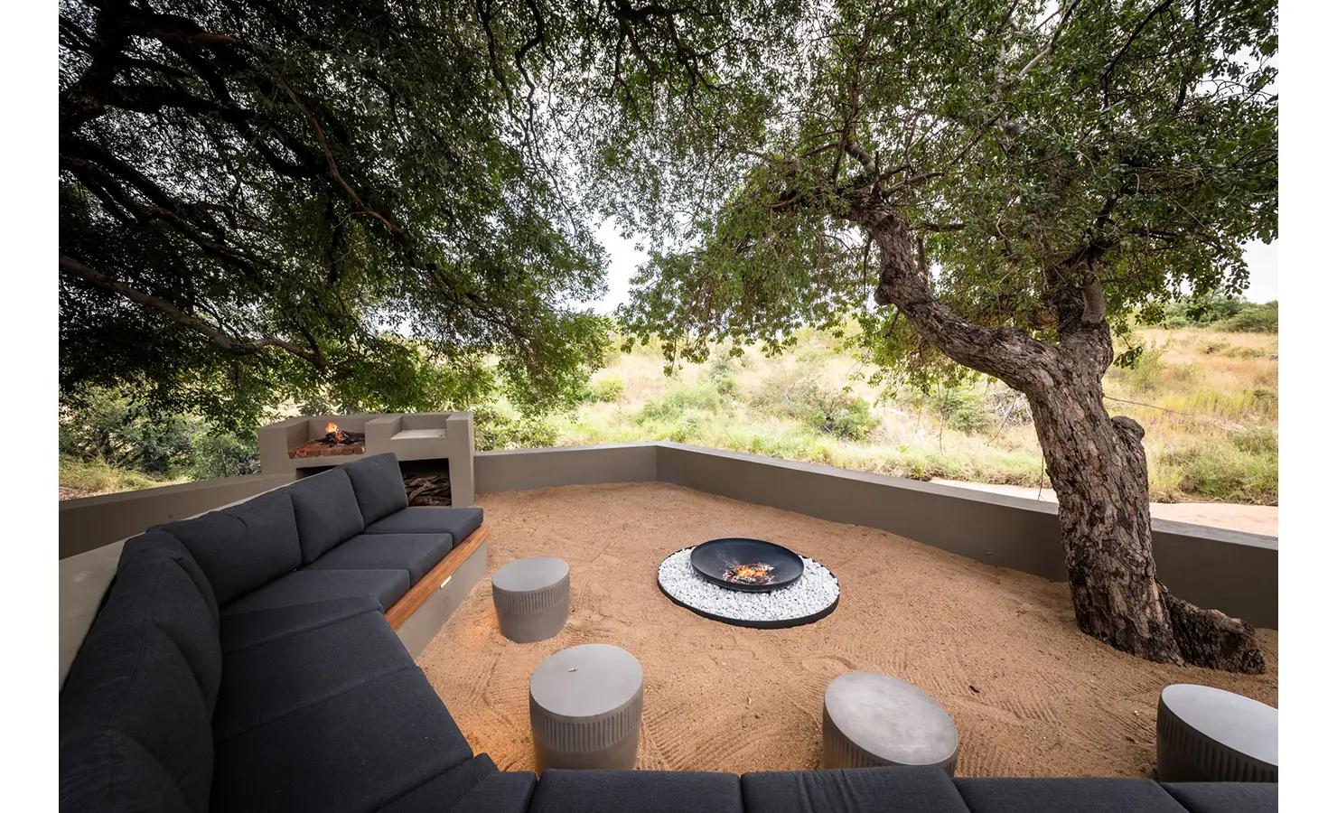 Perfect Hideaways: An outdoor fire pit lounge with comfortable seating under a canopy of trees, offering a cosy space to enjoy the wilderness. Tulela Lodge, Klaserie Private Nature Reserve.