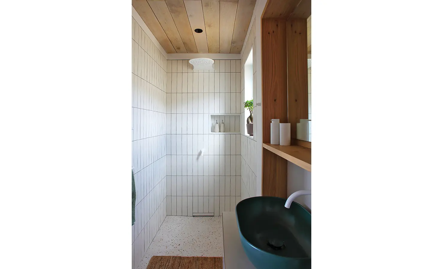 Perfect Hideaways: A modern walk-in shower with clean white vertical tiles, a sleek rainfall showerhead, and a wooden vanity with a deep green basin, adding a natural and contemporary touch. Flamingo, Churchhaven.